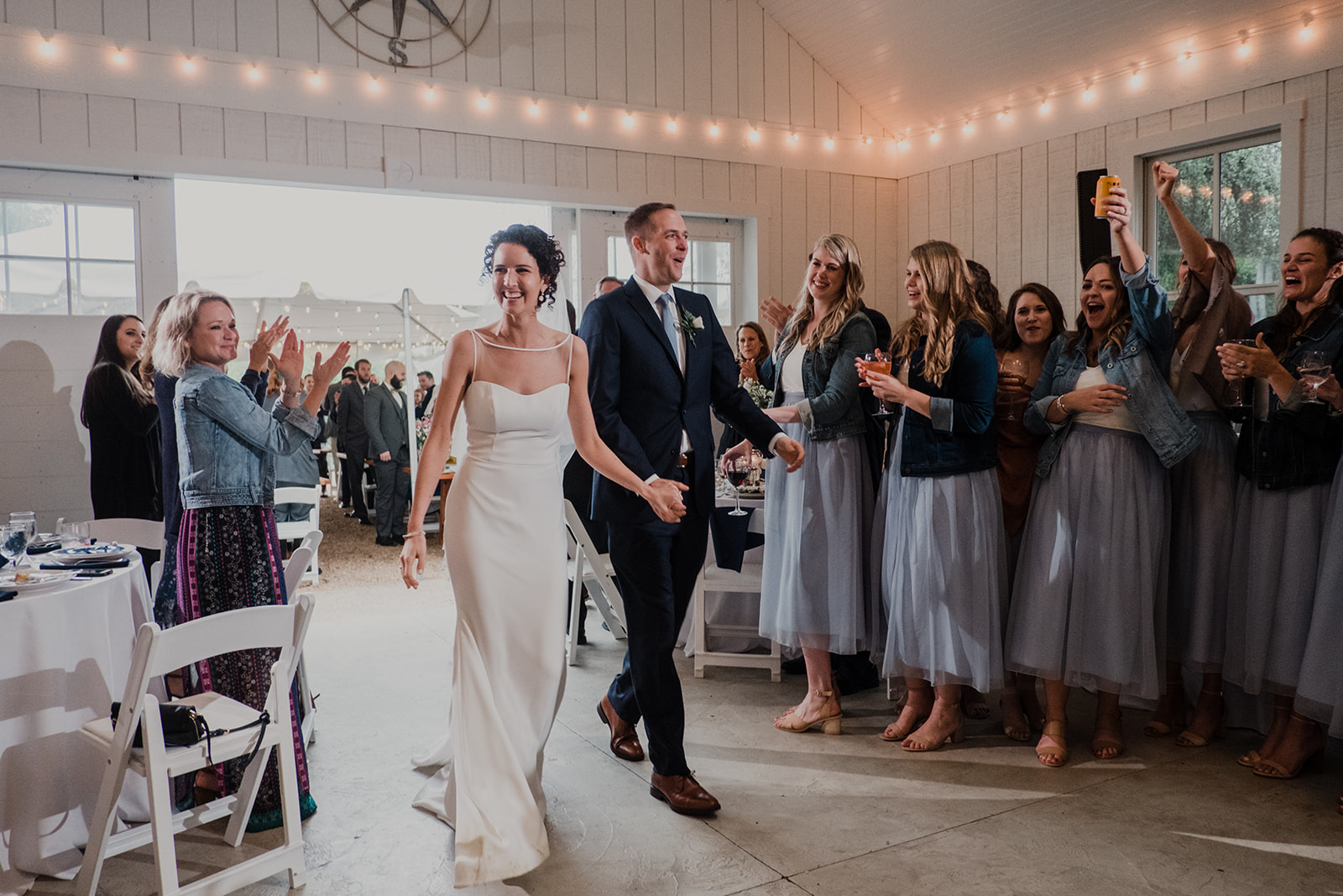 A bride and groom are applauded by guests as they walk into their wedding reception at Blue Hill Farm in Waterford, VA