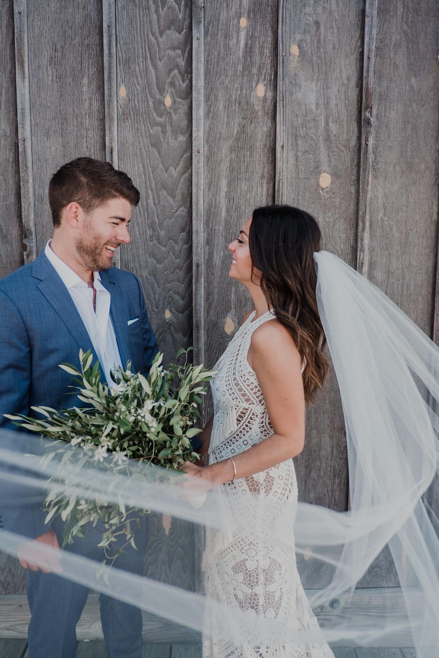 bride and groom check each other out during first look with bride's veil blowing in the wind