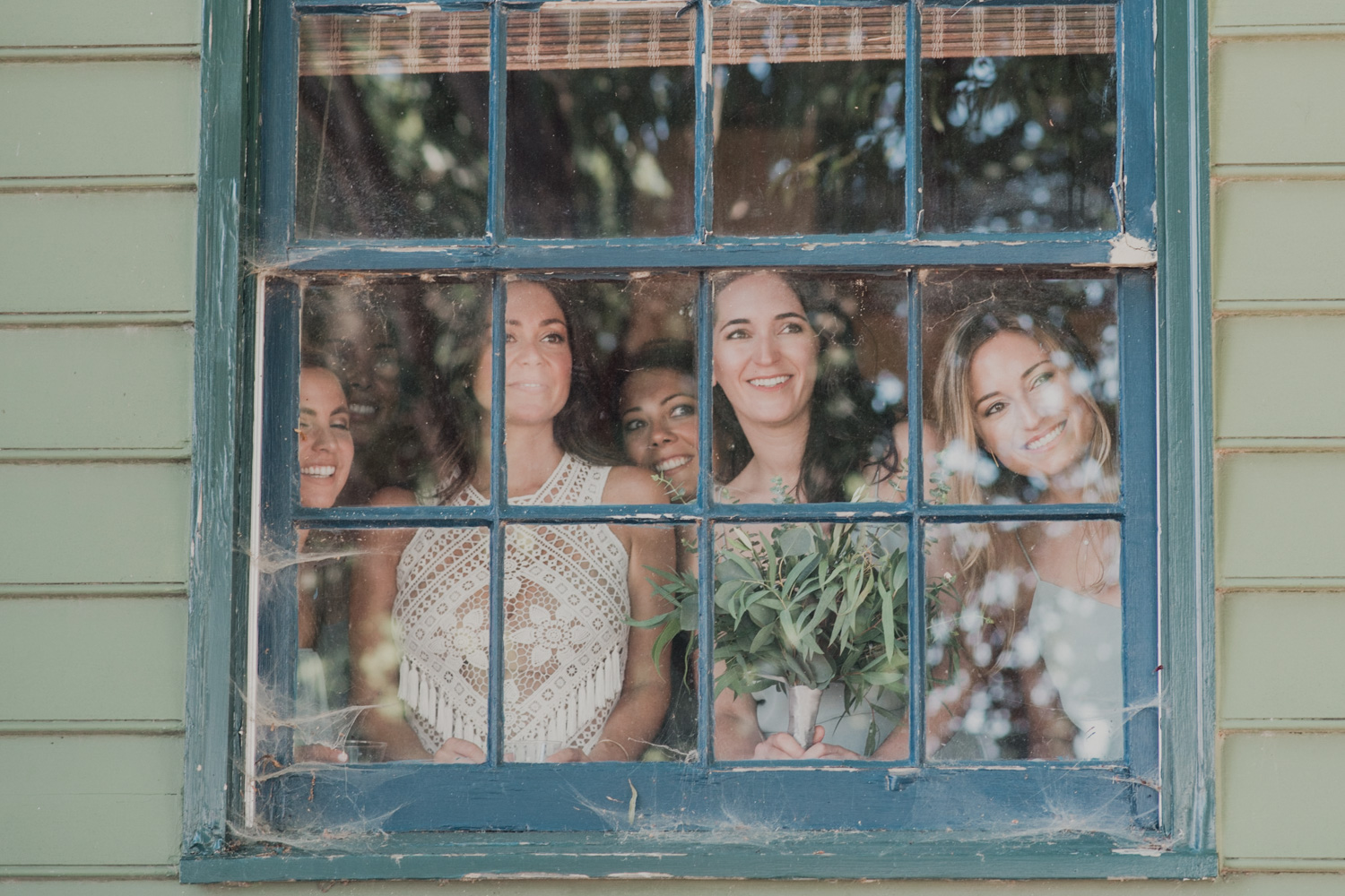 bride and bridesmaids look out window as guests arrive