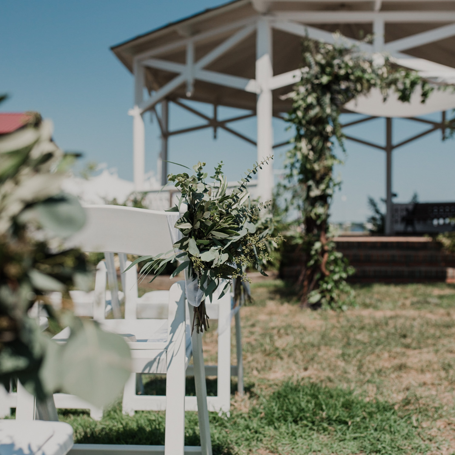 closeup of greenery decorations on wedding ceremony chairs