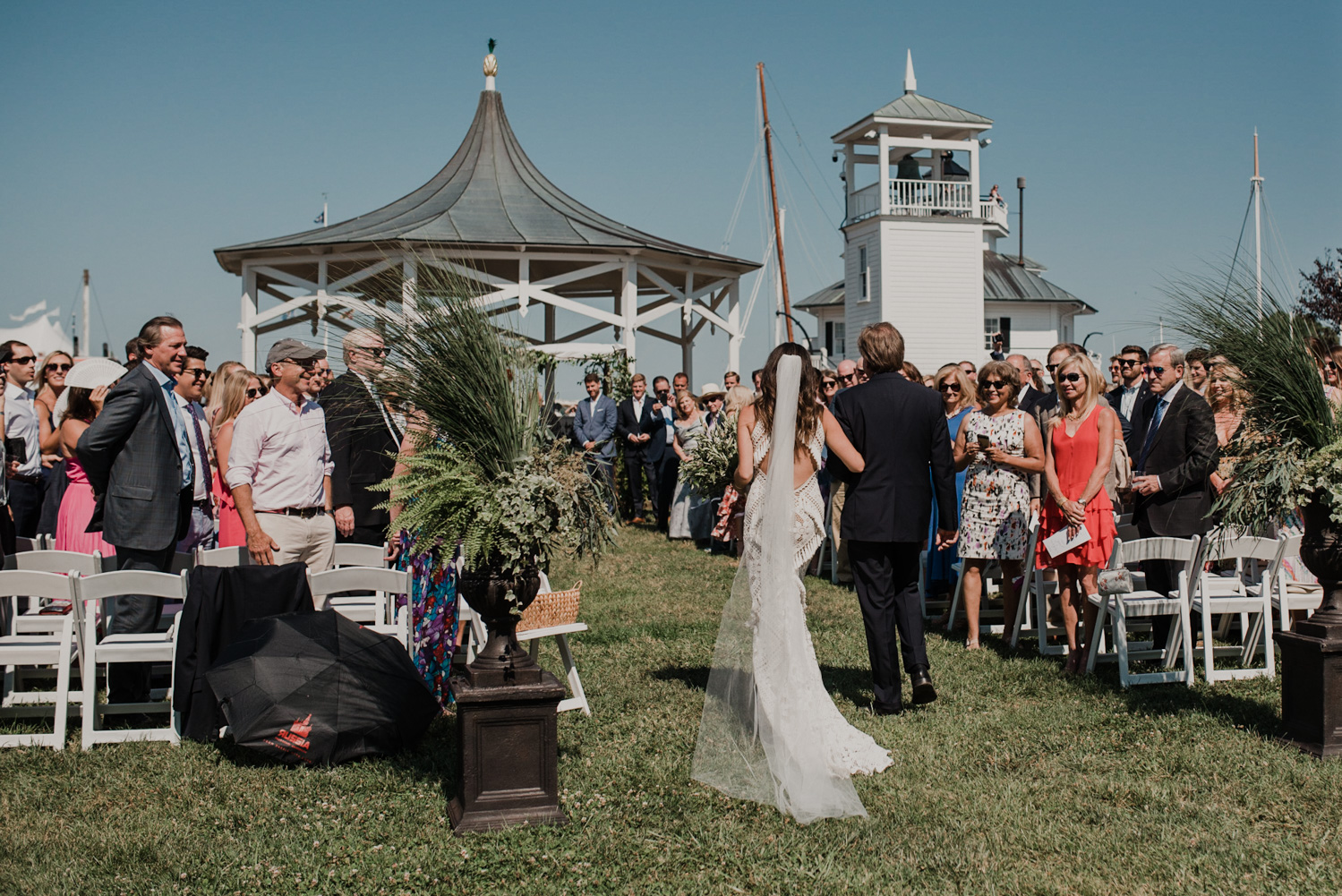 bride and her father walk down the aisle with all of the guests and the groom in the background