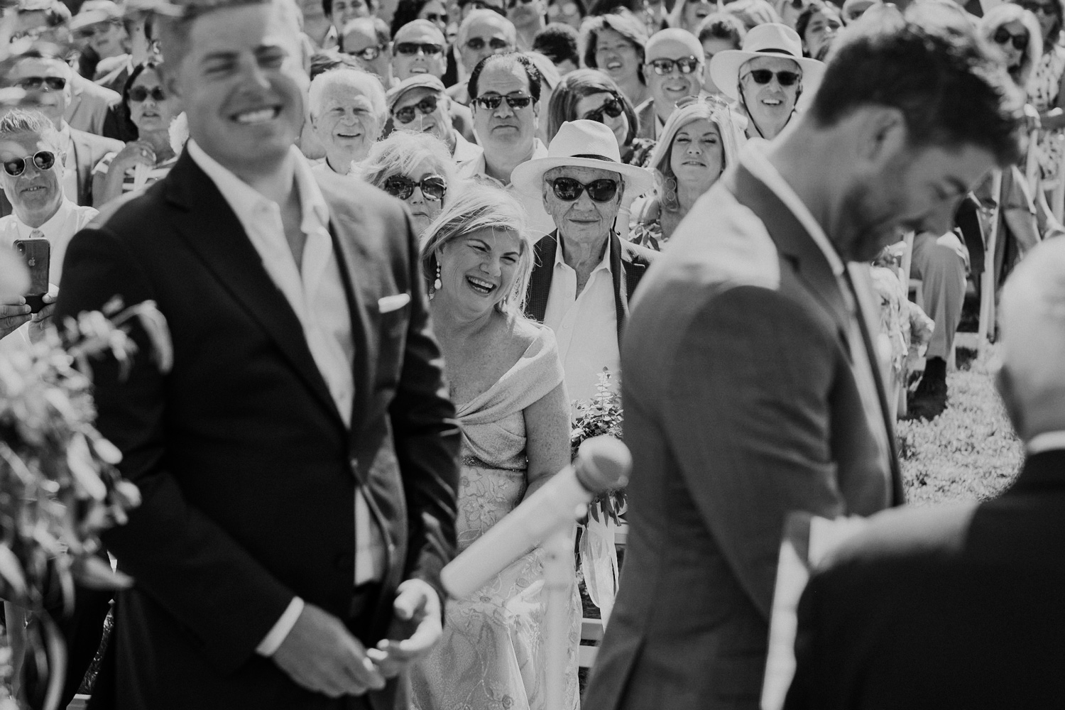 Groom's mother smiles as she watches her son get married during the vows
