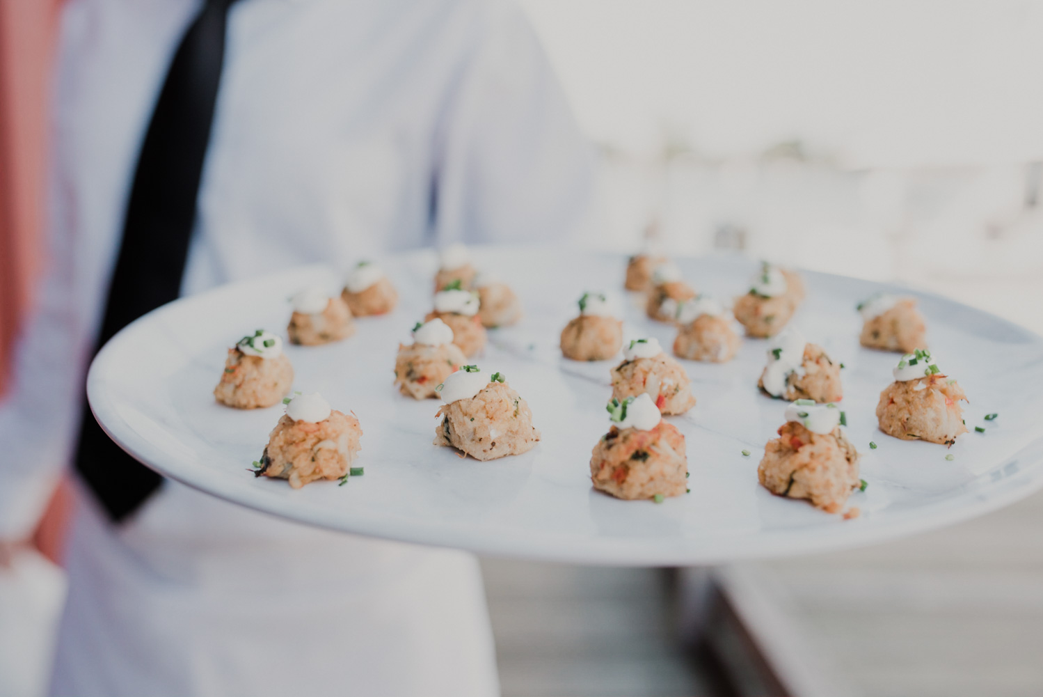 gourmet by the bay server hands out crab cake appetizers during cocktail hour