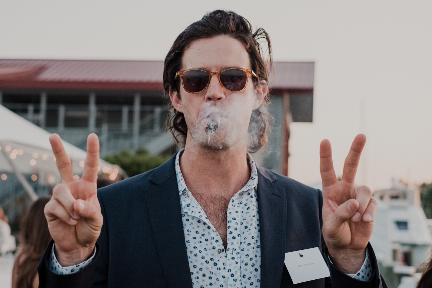 wedding guest smokes cigar and holds up double peace signs