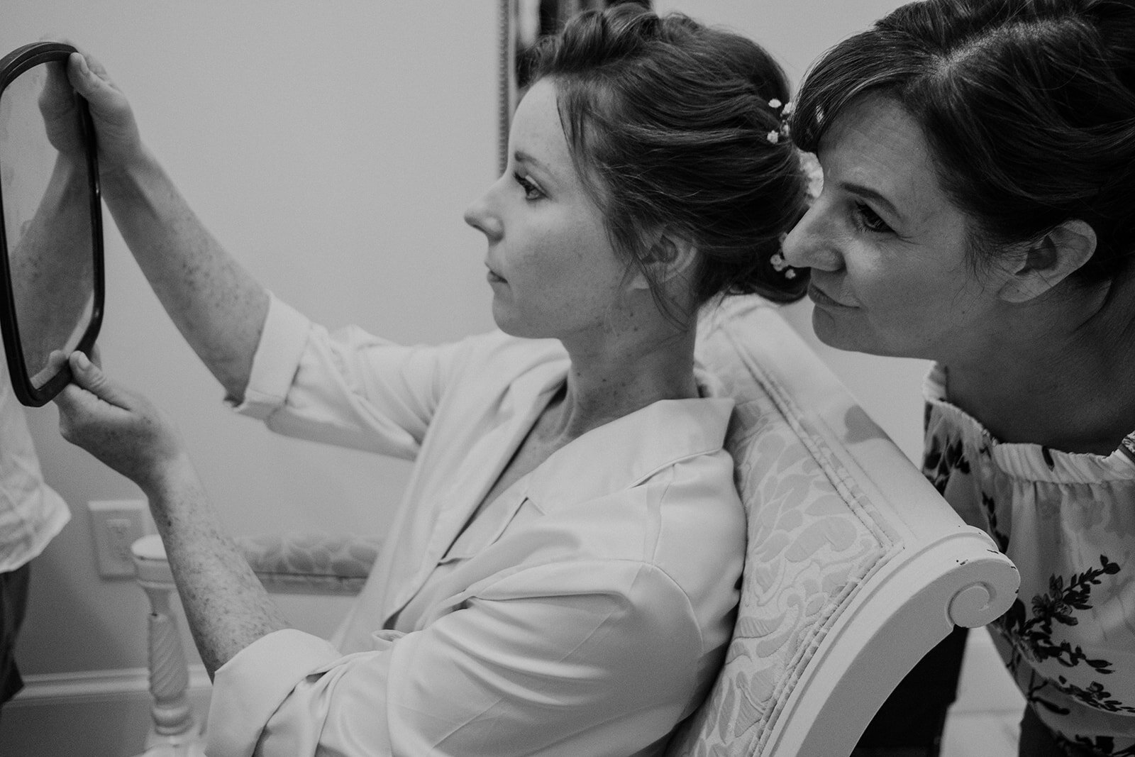 The mother of the bride peeks over the bride's shoulder as she looks into a mirror to check her hair and makeup at the Birkby House in Leesburg, VA. 