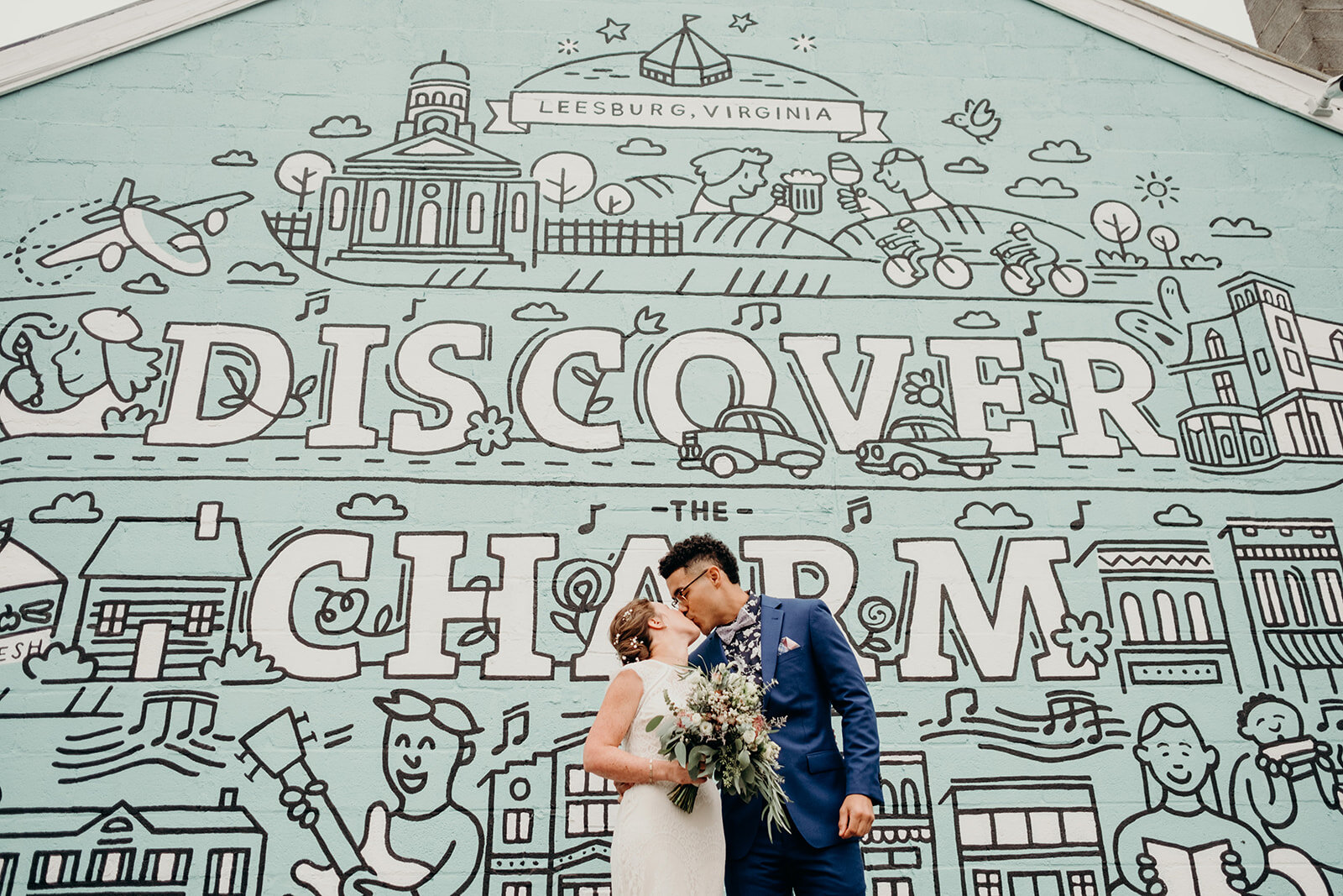 A bride and groom kiss in front of a mural in downtown Leesburg, VA.