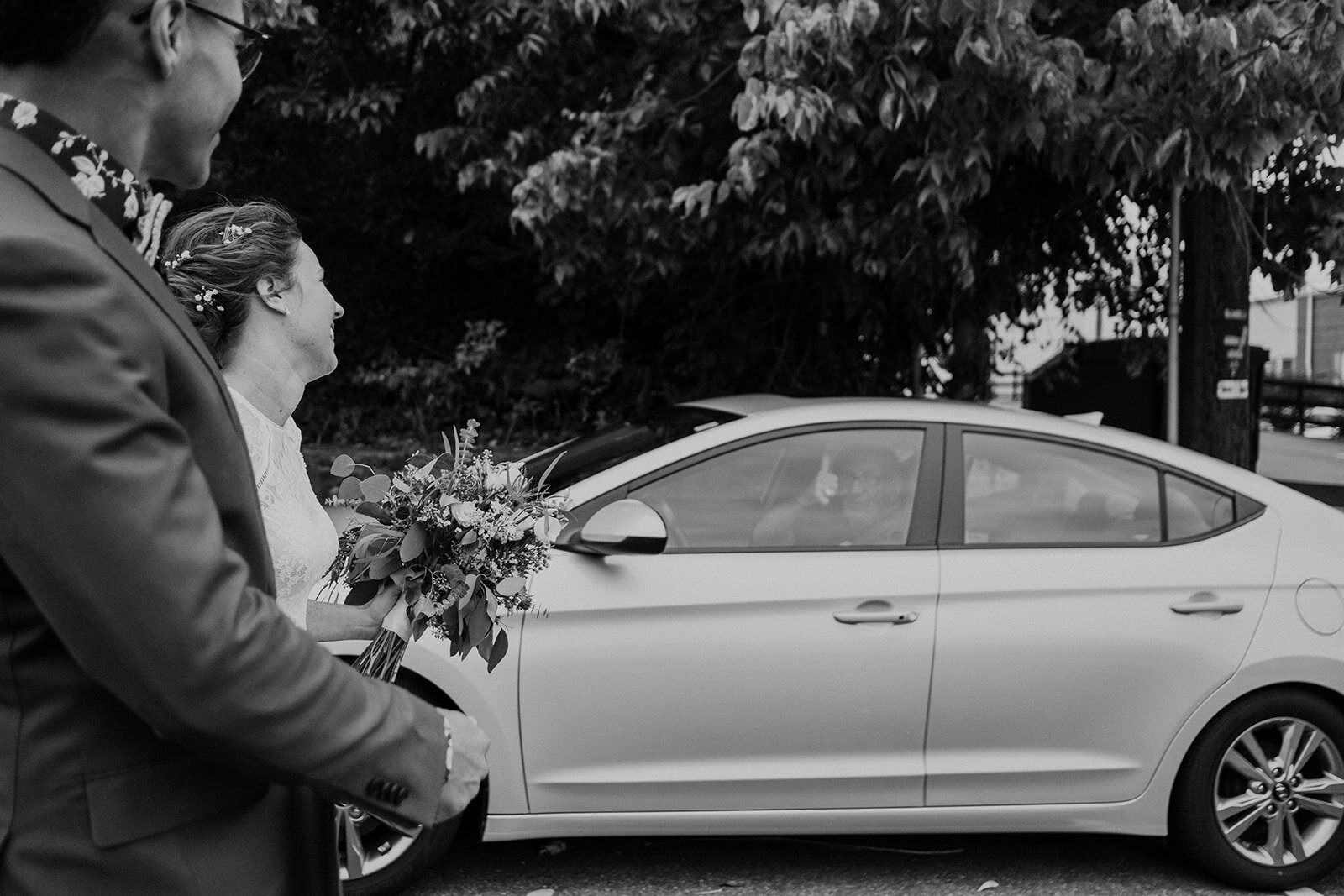A man in a car gives a thumbs up to the bride and groom on their wedding day in Leesburg, VA.