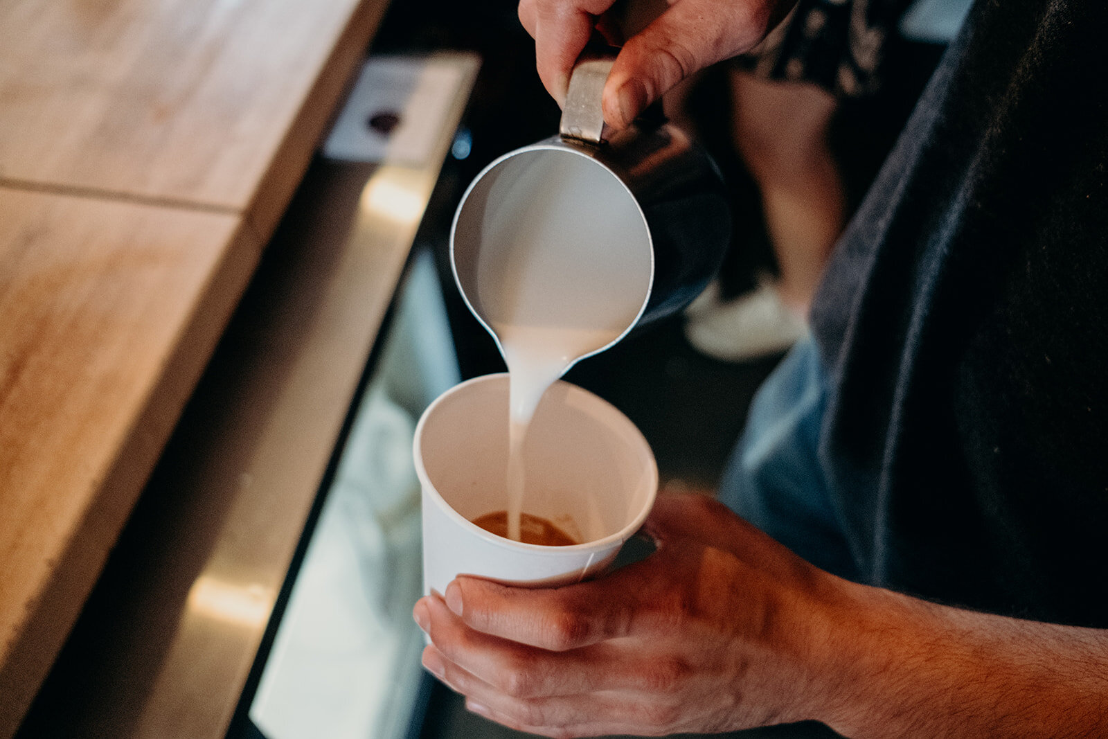 A barista at King Street Coffee in Leesburg, VA pours the oat milk into the drink he is making for the bride on her wedding day. 