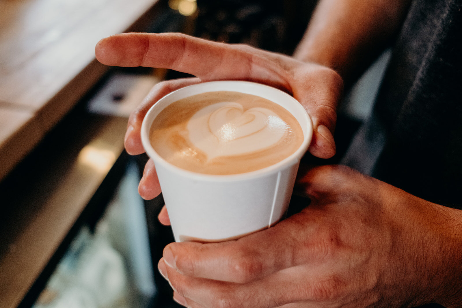 A barista at King Street Coffee presents a perfectly poured latte with a heart for the bride on her wedding day. 