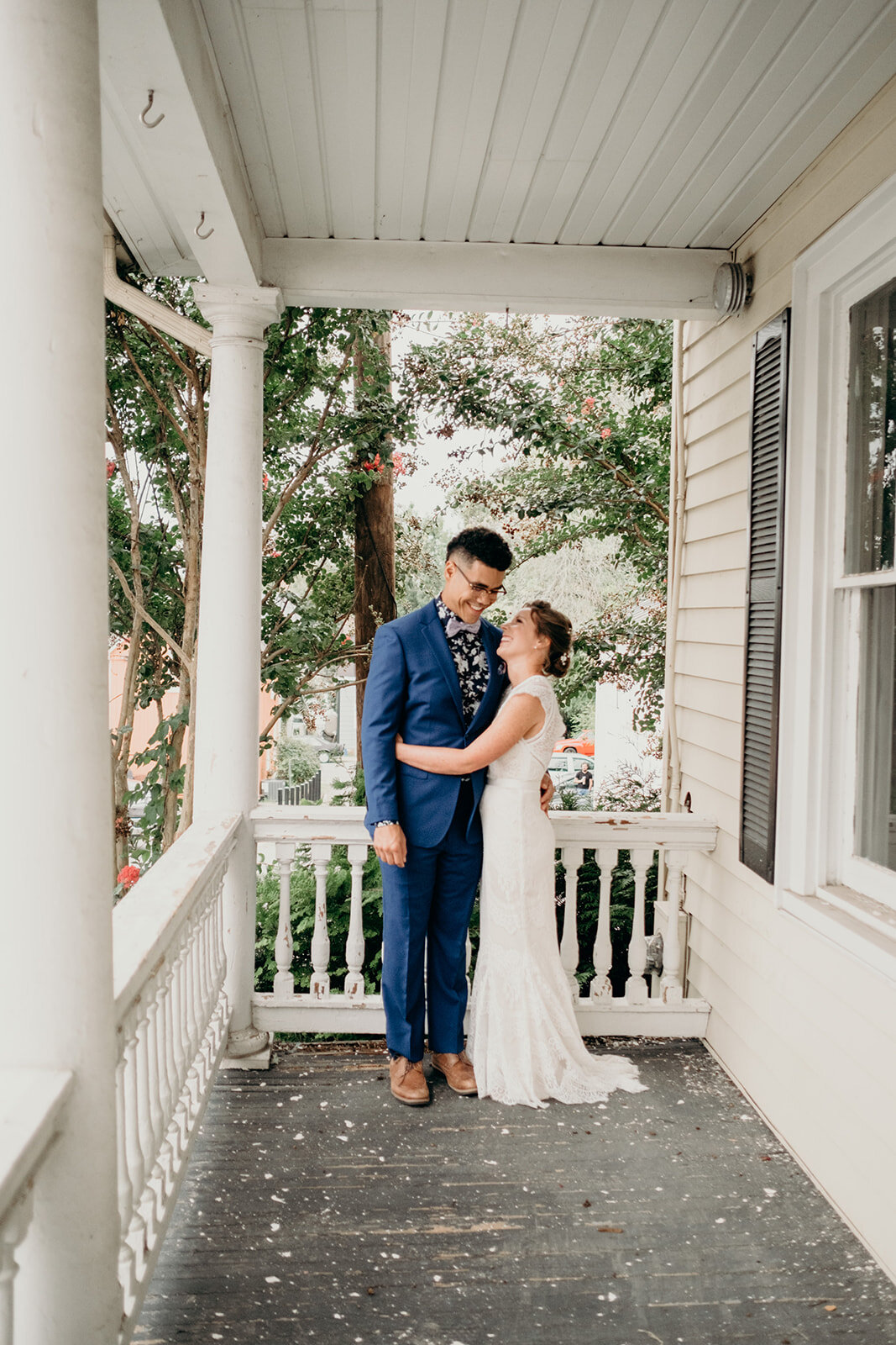 A bride and groom snuggle on a porch in downtown Leesburg, VA.
