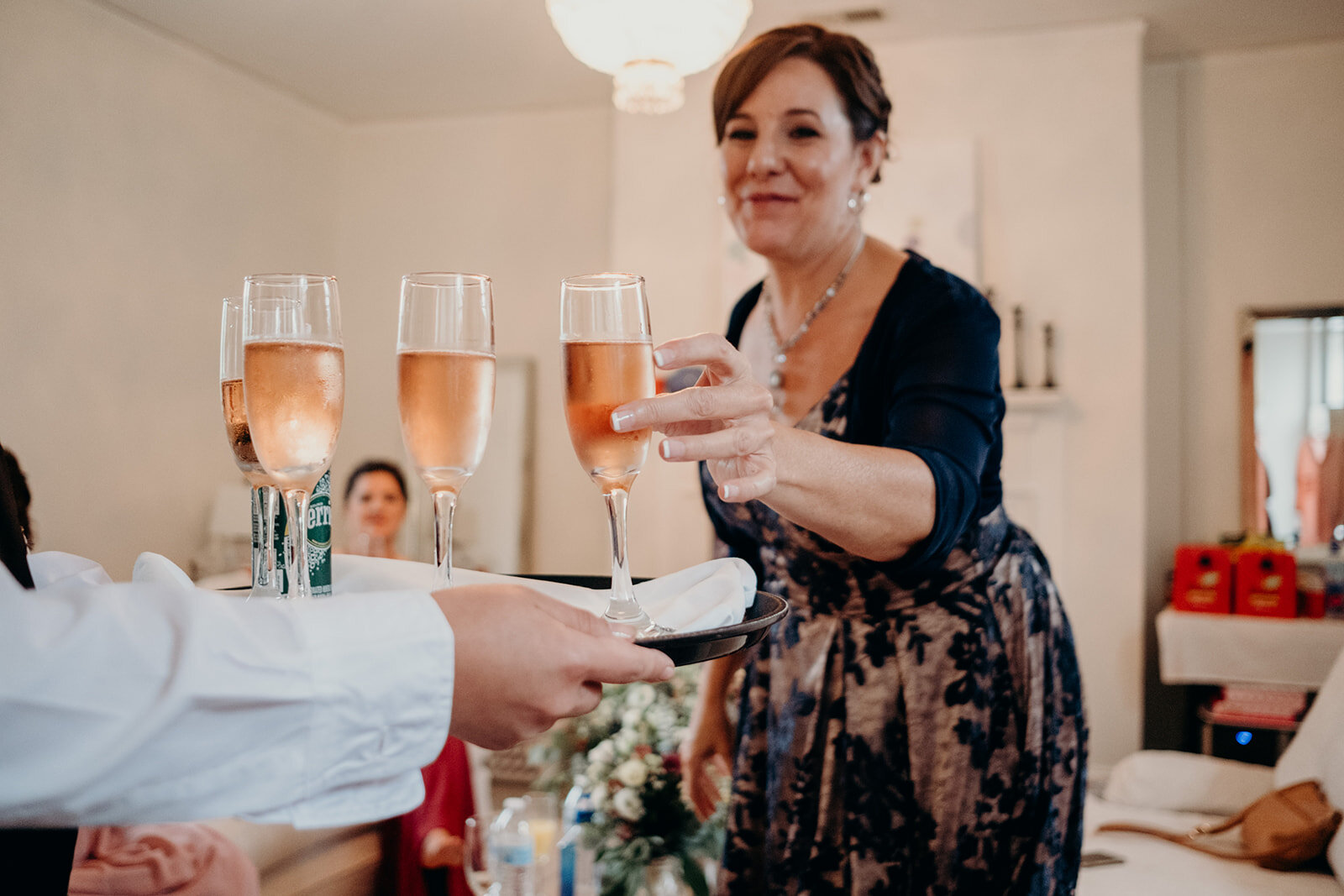 The mother of the bride takes a glass of champagne to toast her daughter before she walks down the aisle. 