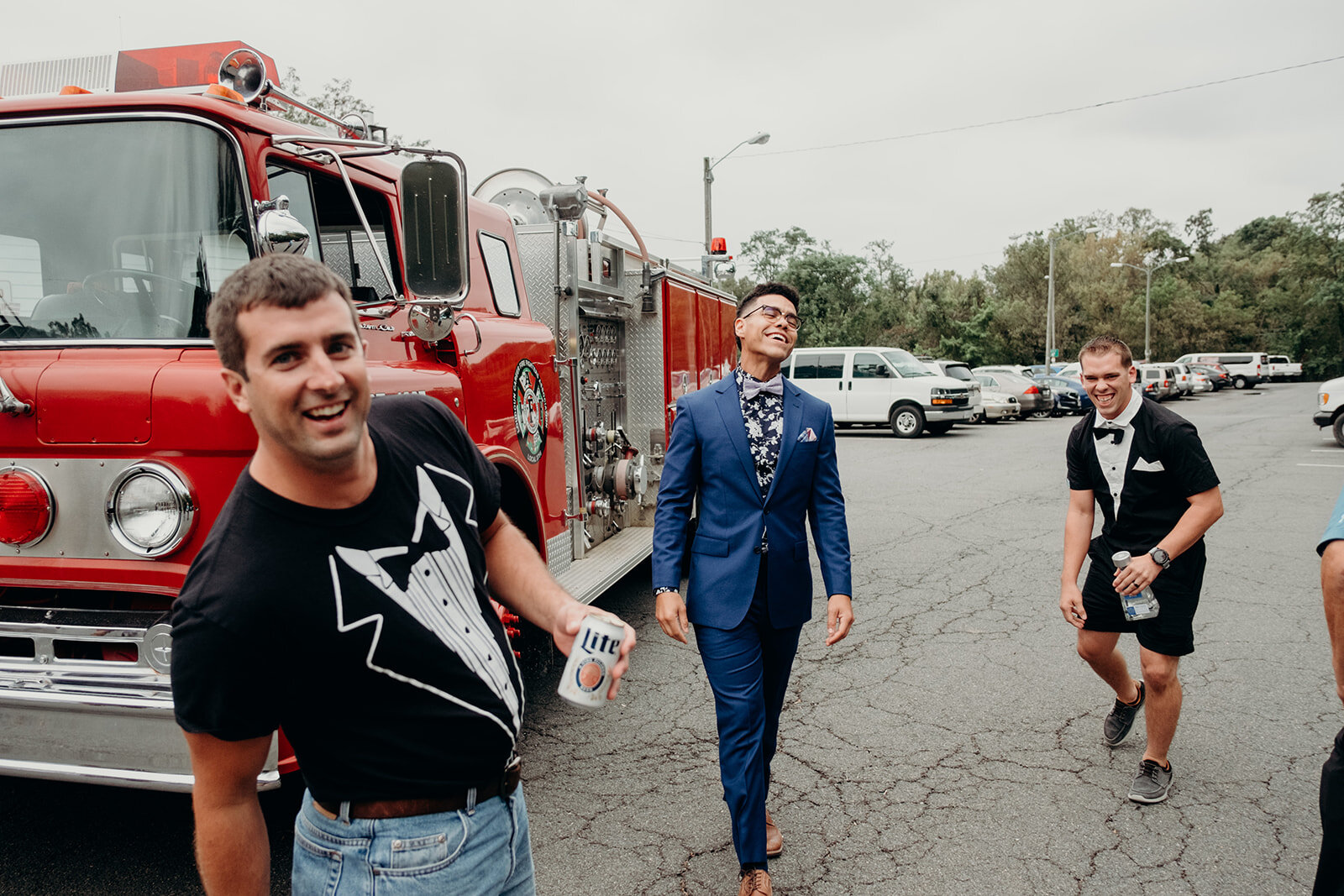 A groom and two of his friends prepare to ride a fire truck into an outdoor wedding ceremony. 