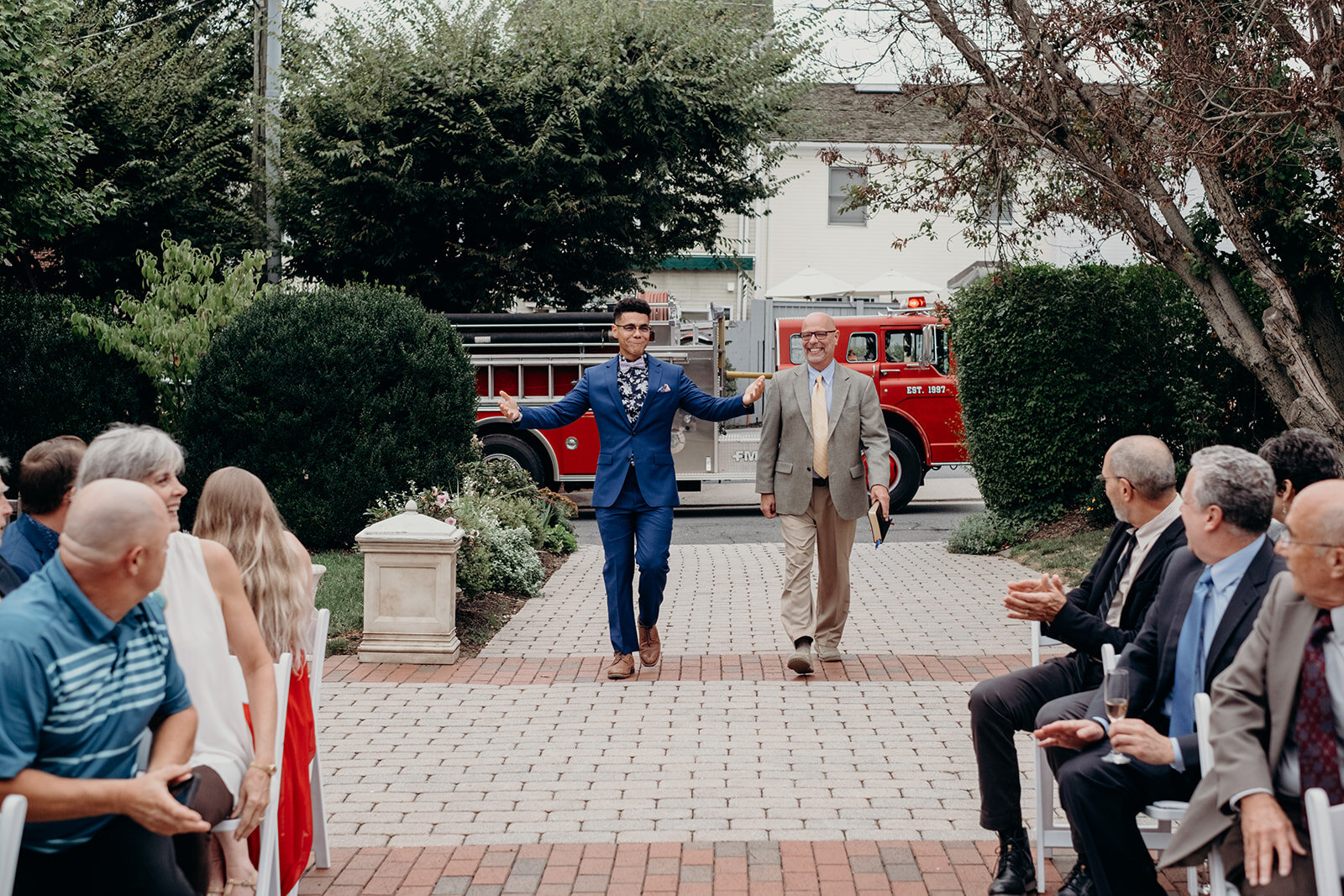 A groom and the officiant walk down the aisle at an outdoor wedding ceremony at Birkby House at Leesburg, VA.