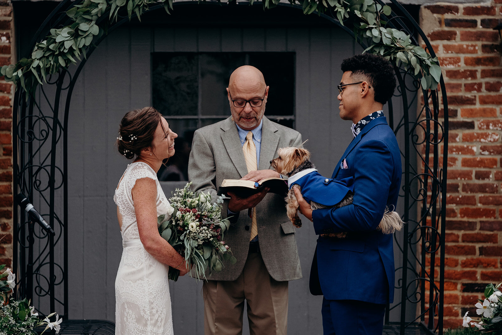 A bride and groom stand in front of their officiant during their outdoor wedding ceremony at Birkby House in Leesburg, VA. 