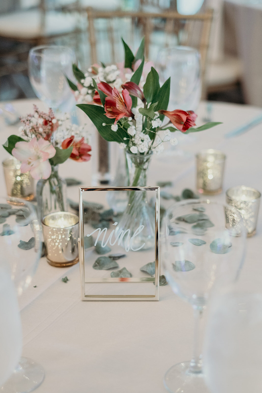 Delicate flowers and candles decorate tables at a tented wedding reception at Birkby House in Leesburg, VA. 