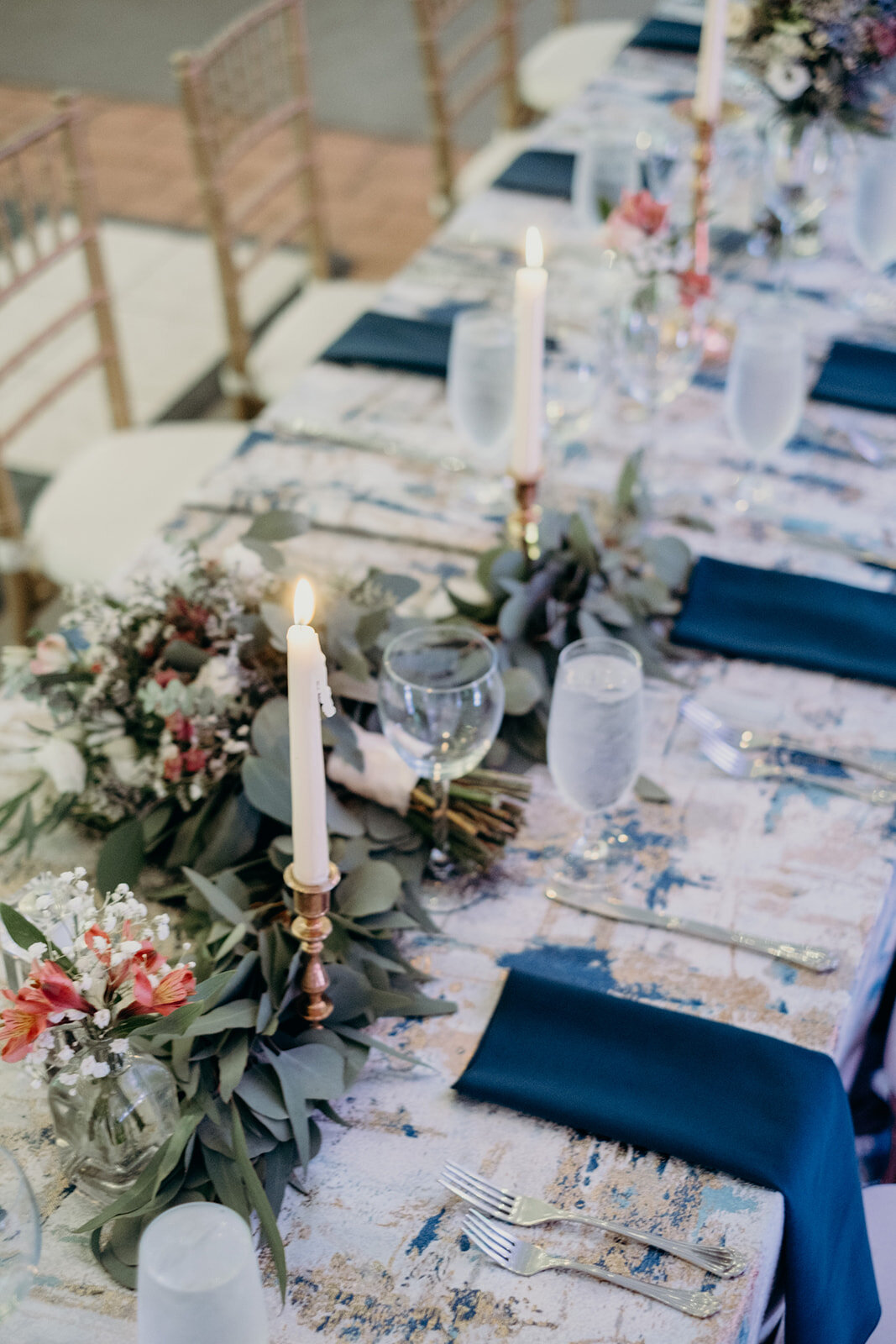 Blue and golds and greens adorn the head table at a tented wedding reception at Birkby House in Leesburg, VA.