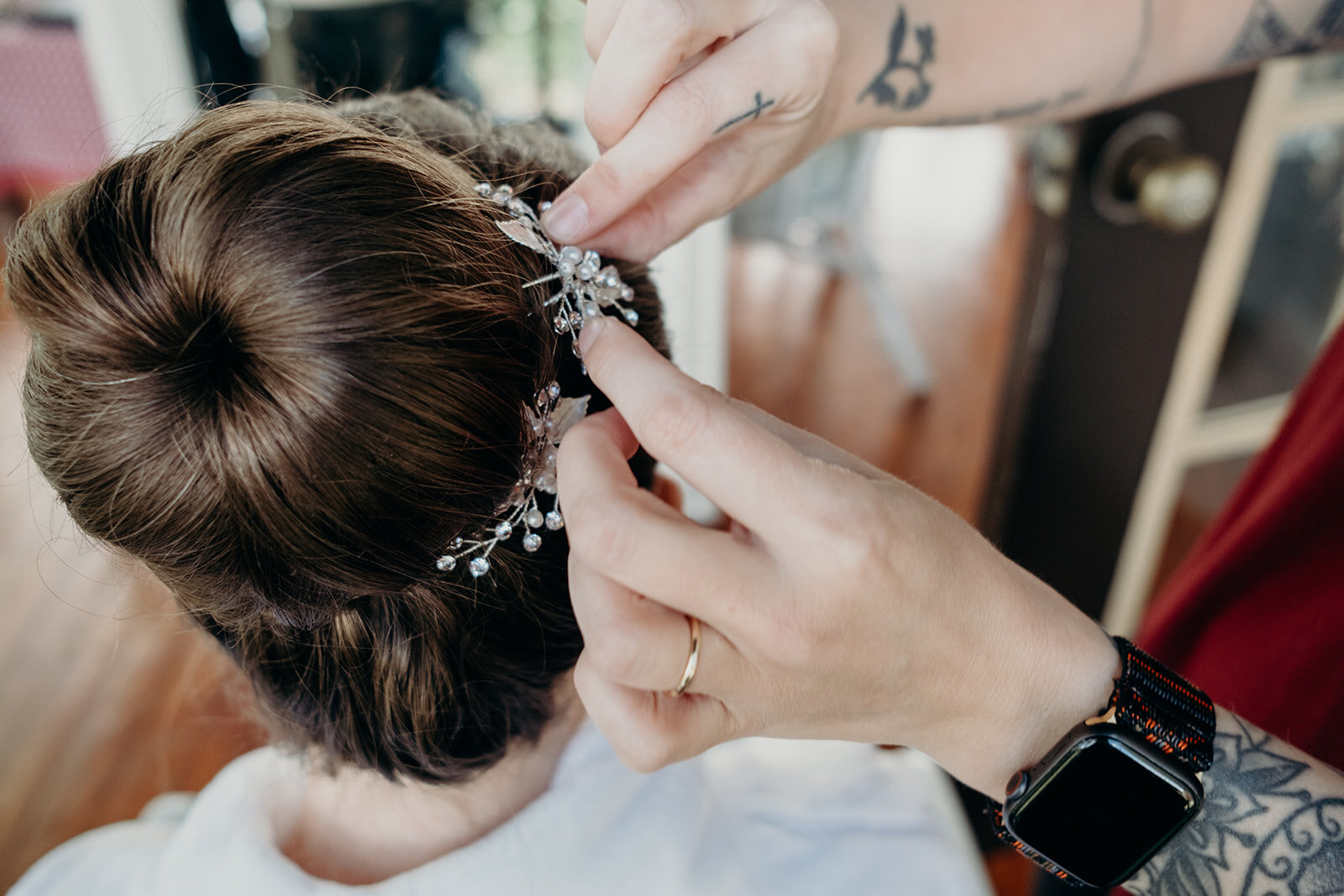 A bride gets a jeweled accent placed on her high ballerina bun before her outdoor farm wedding. 