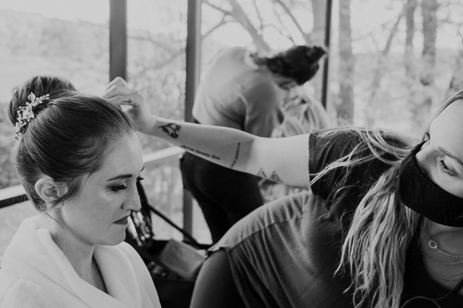 A hairstylist checks the bridal updo before the outdoor farm wedding ceremony.