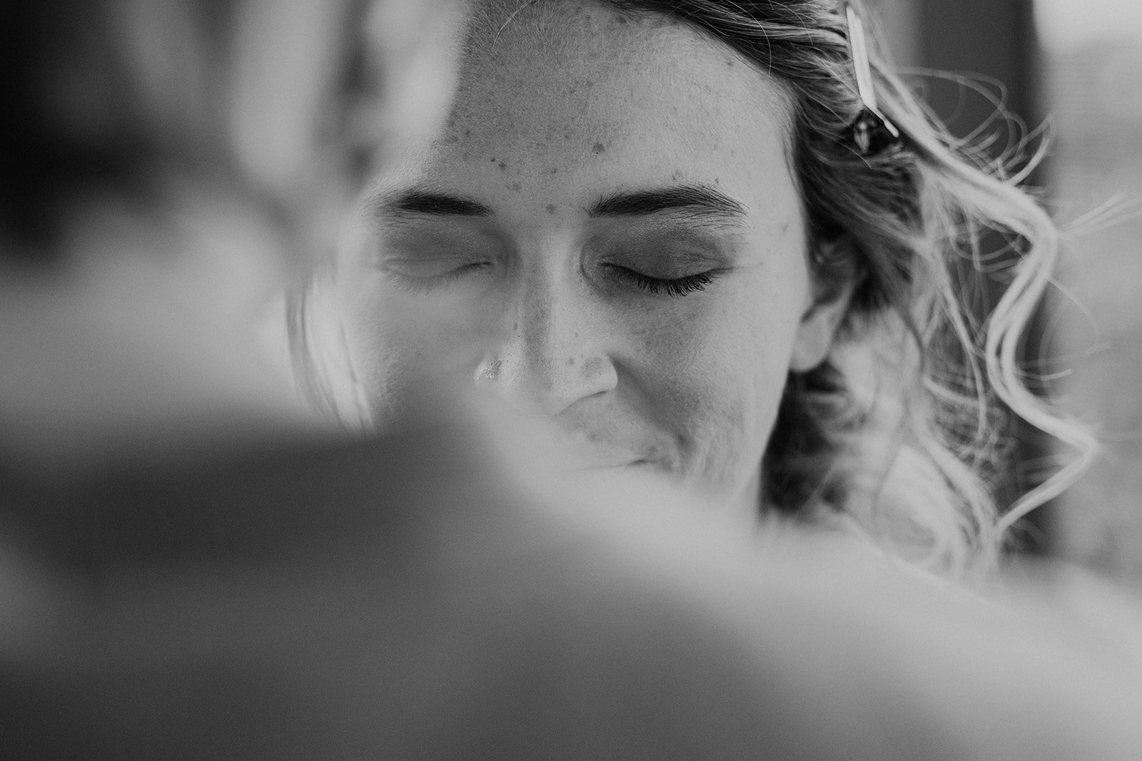 The sister of the bride smiles while getting her makeup done before the outdoor farm wedding ceremony. 