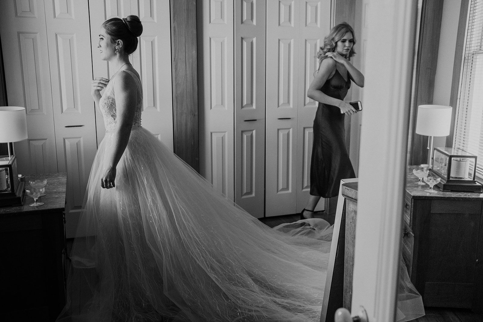 A bride looks out the window after putting on her wedding dress on her wedding day.