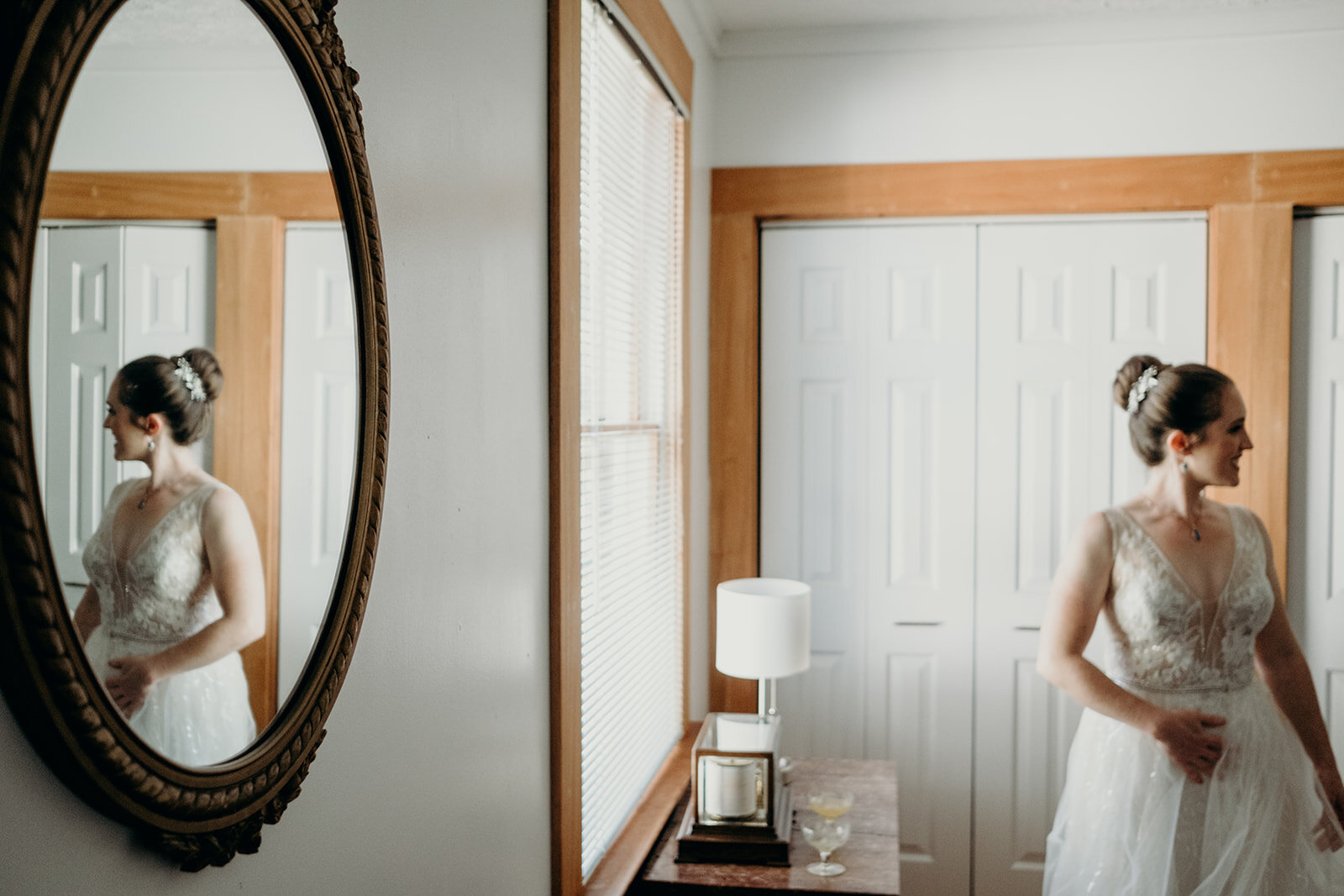 A bride looks at her sister while her image is reflected on her wedding day.