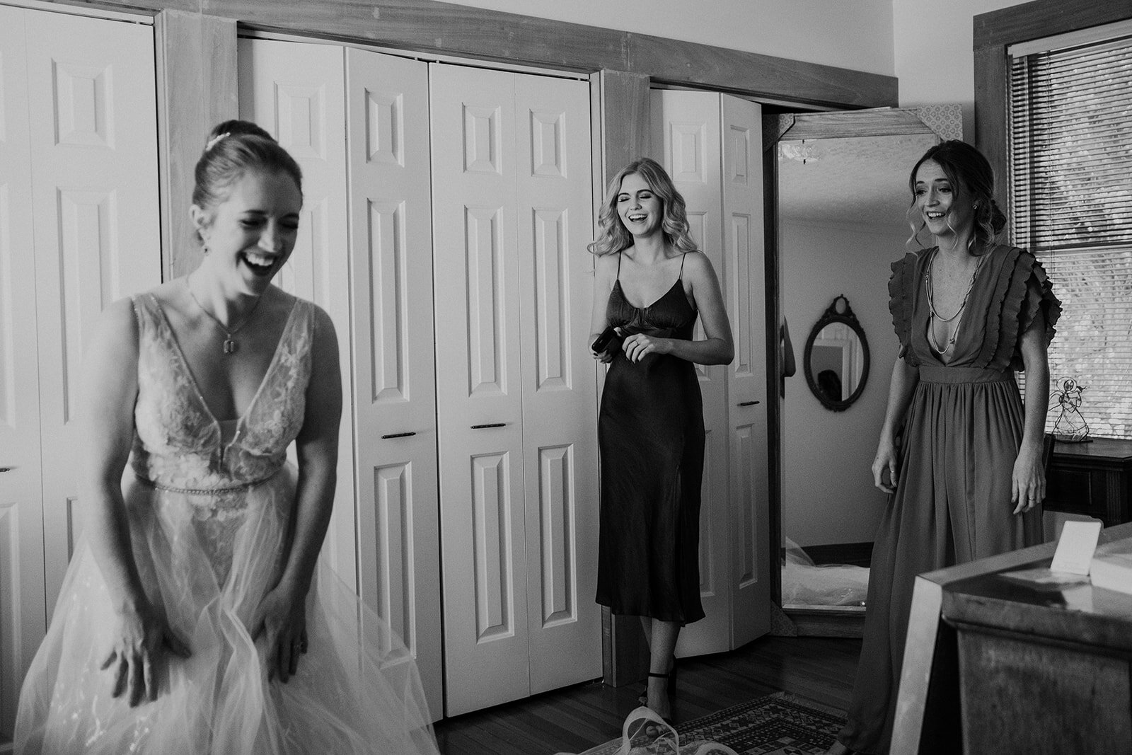 A bride laughs with her sisters after they helped her put on her wedding dress.