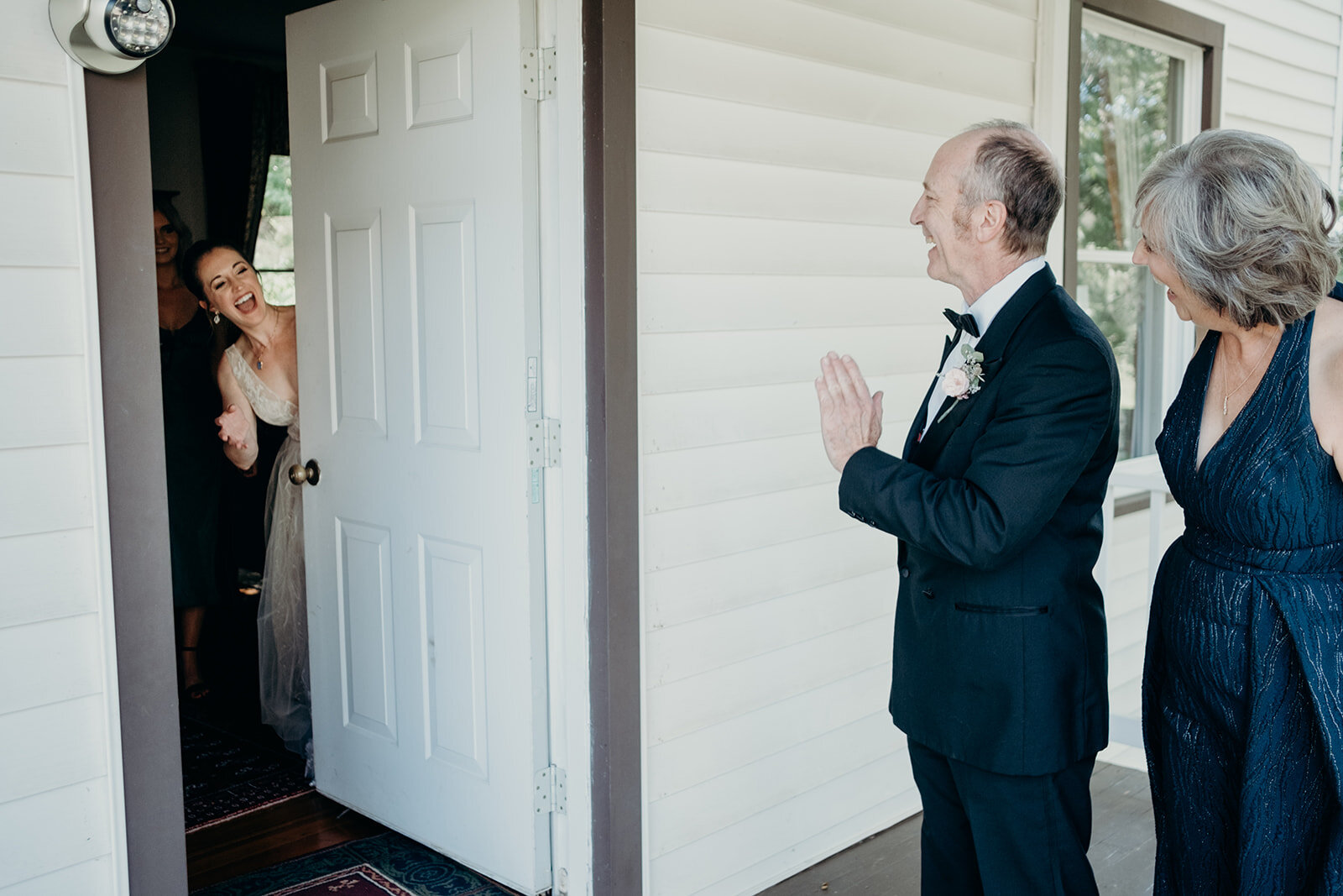 A bride peeks out at her father right before her outdoor farm wedding ceremony.