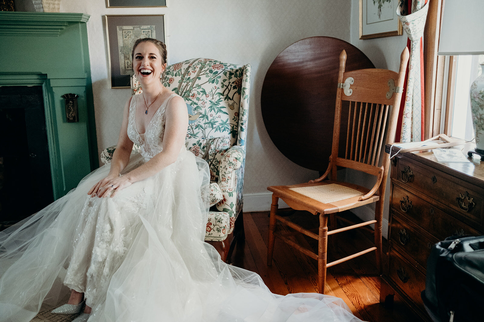 A bride sits in the living room of a old farmhouse before her outdoor ceremony.
