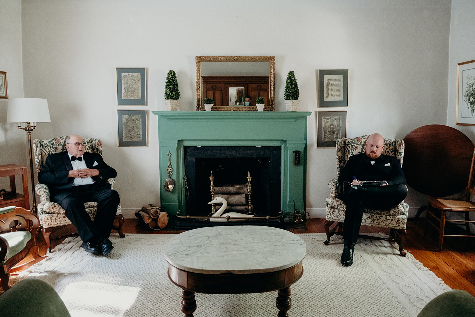 A groom works on his vow while sitting across from his father in an old farmhouse before his outdoor wedding ceremony.
