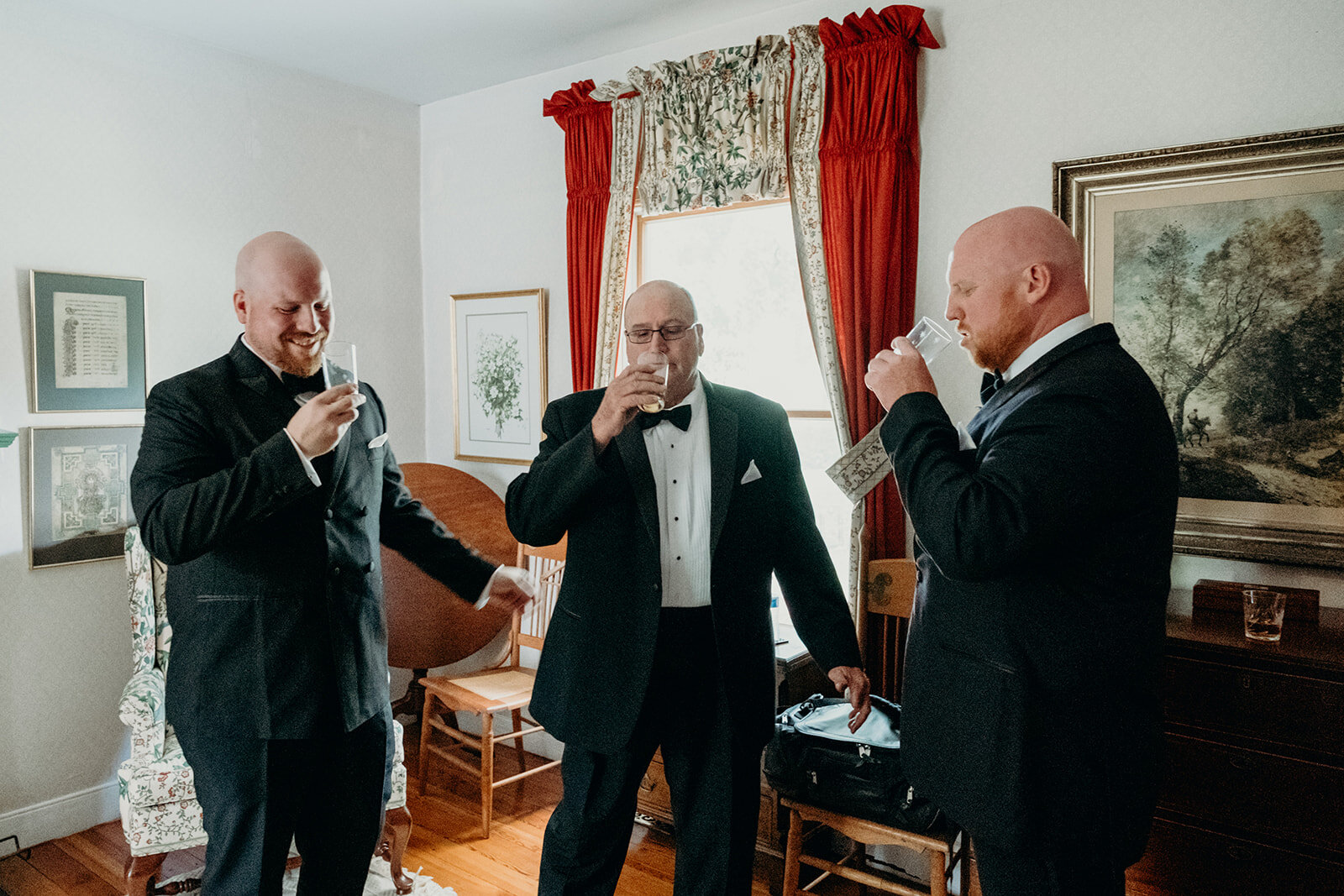 A groom takes a drink with his brother and his father before his outdoor farm wedding ceremony. 