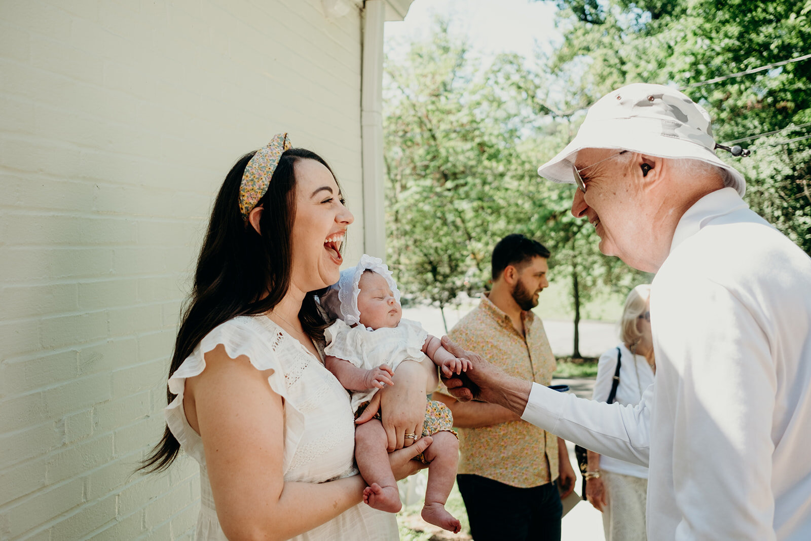 A man greets his granddaughter and great granddaughter before a Jewish baby naming ceremony.