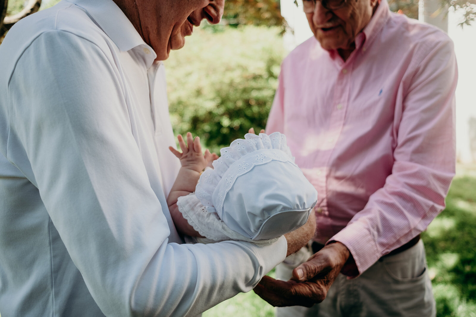 Great grandfathers hand off their great granddaughter during a Jewish baby naming ceremony.