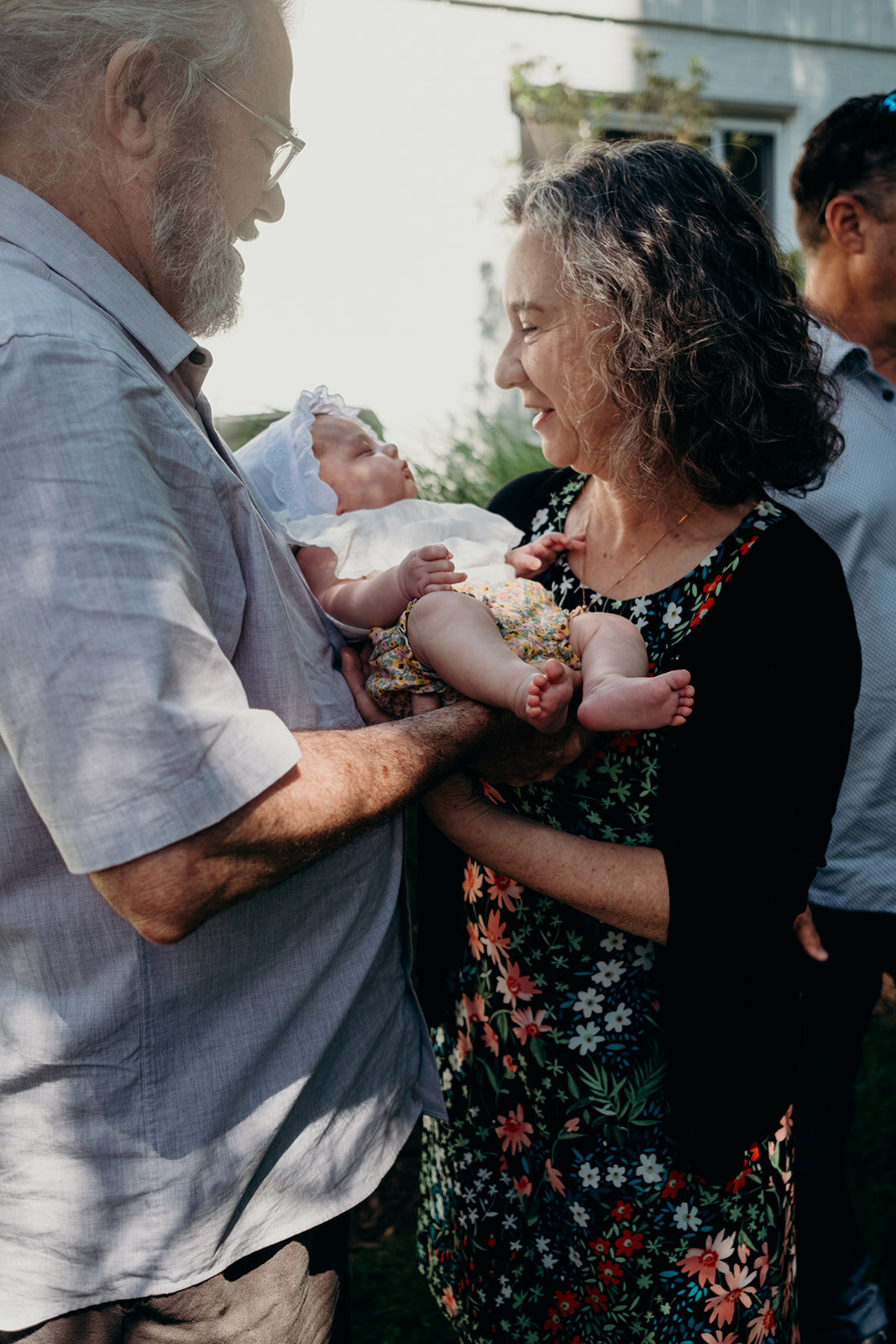 A grandfather hands his granddaughter to her grandmother during a Jewish baby naming ceremony.