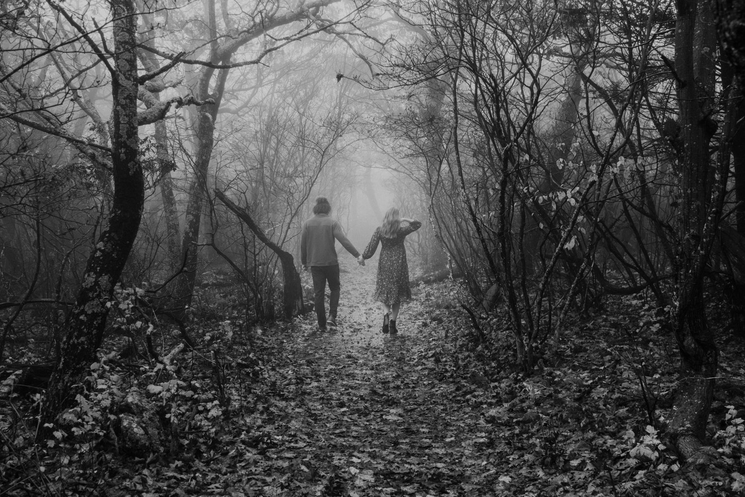 Couple walking through a foggy mountain trail holding hands