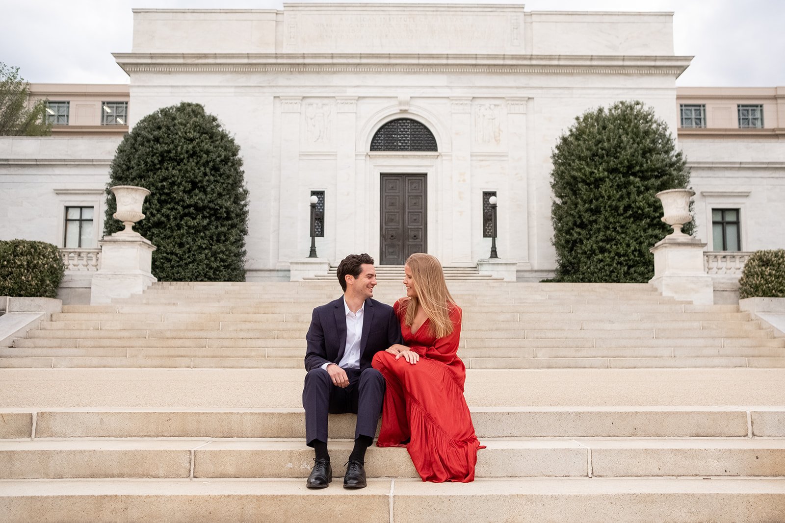A couple sits on the steps of the American Institute of Pharmacy Building in Washington, DC.