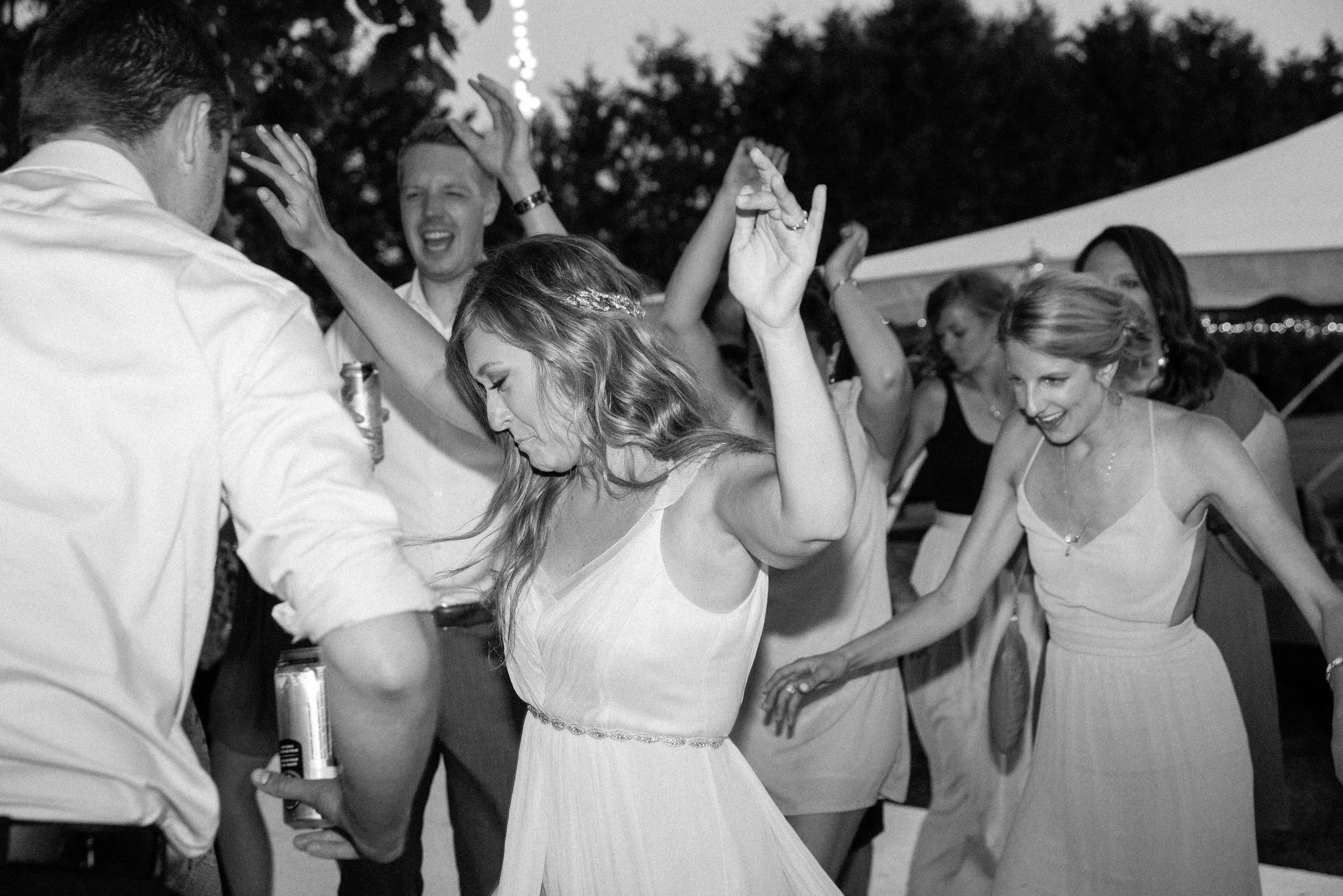 Bride dancing with guests under twinkle lights