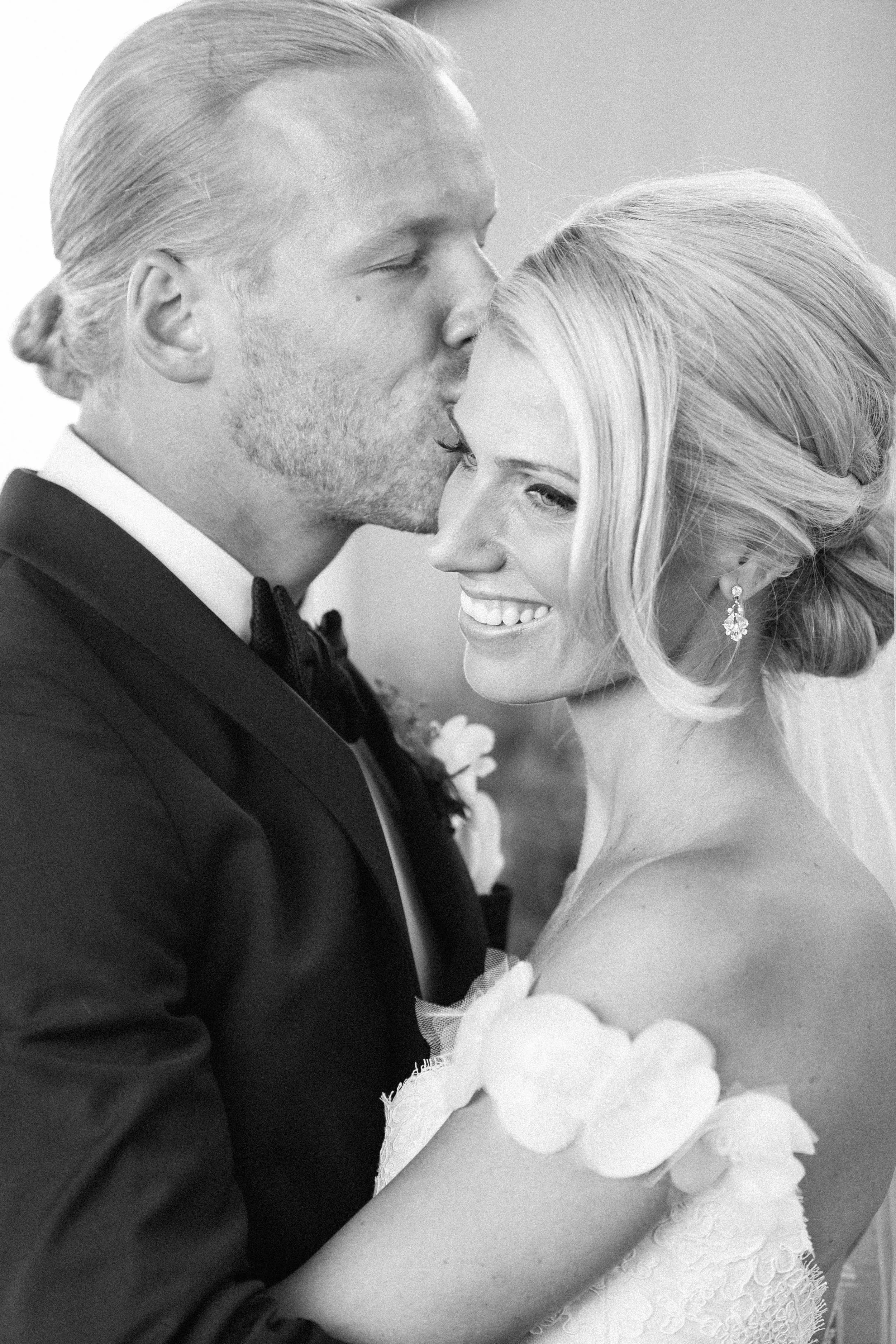 Groom kissing bride outside
