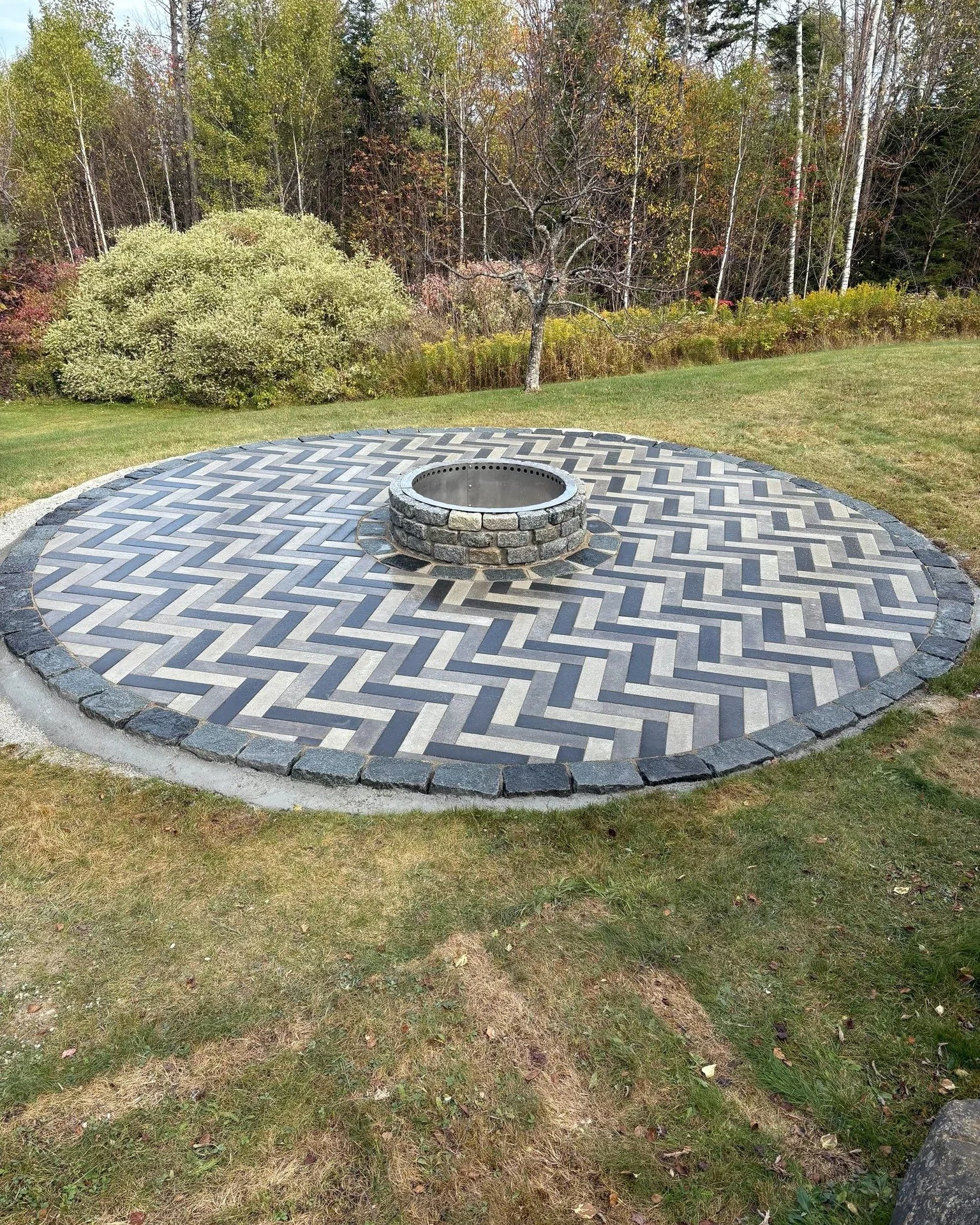 🔥 Backyard Goals in Ludlow 🔥
This circular fire pit patio is the perfect blend of craftsmanship and style.

✨ Ideal Straightline pavers laid in a timeless herringbone pattern
🖤 Black granite cobble border for a bold, refined edge
🩶 Grey granite c
