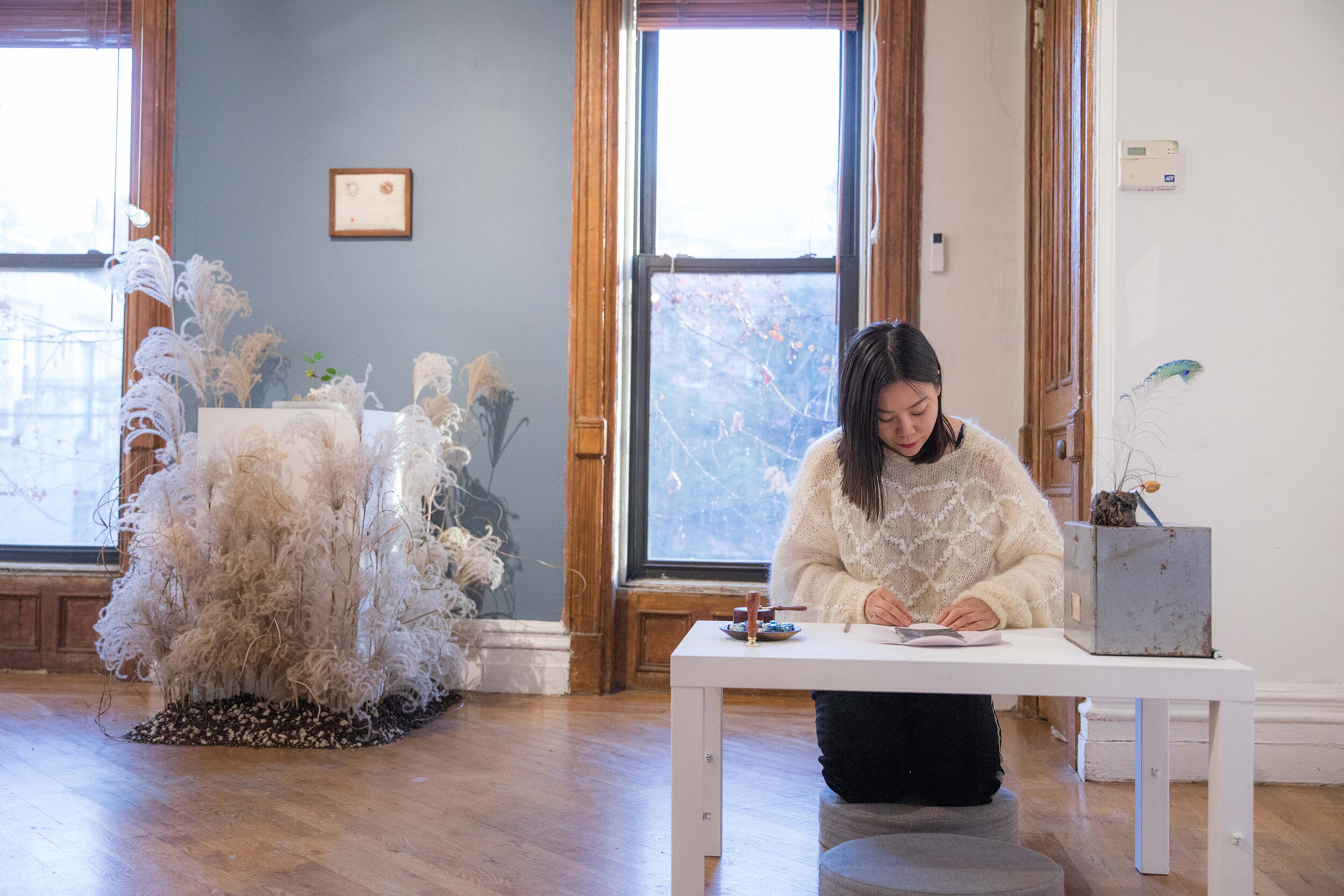   Meng Du: Embers  opening, visitor writing a letter to self or others in the past or future. Photograph by Nadia Peichao Lin. ©Meng Du, courtesy Fou Gallery. 