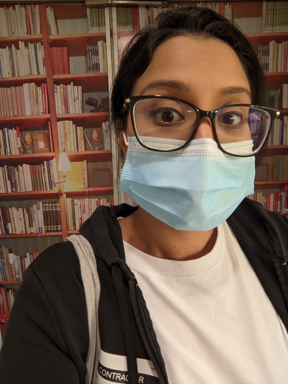 Christine's selfie in front of a fake library mural at a facility audit. 