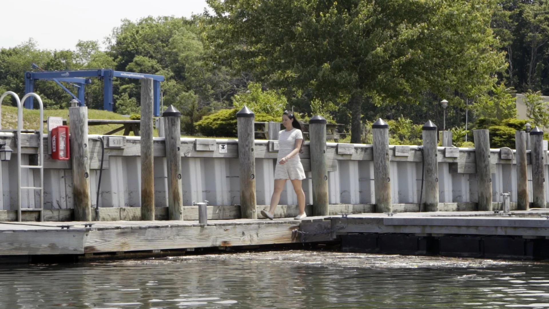 A woman walking along a dock in front of a bulkhead.