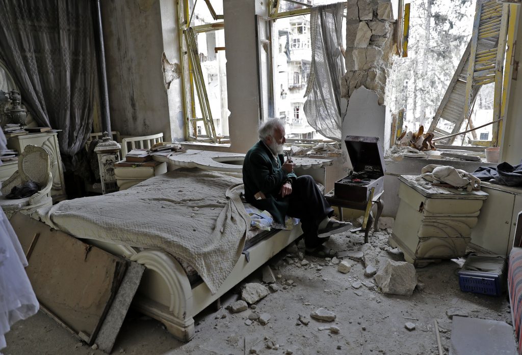 Mohammed Mohiedin Anis, or Abu Omar, 70, smokes his pipe as he sits in his destroyed bedroom listening to music on his gramophone in Aleppo’s formerly rebel-held al-Shaar neighborhood on March 9. Photo by Joseph Eid/AFP/Getty Images