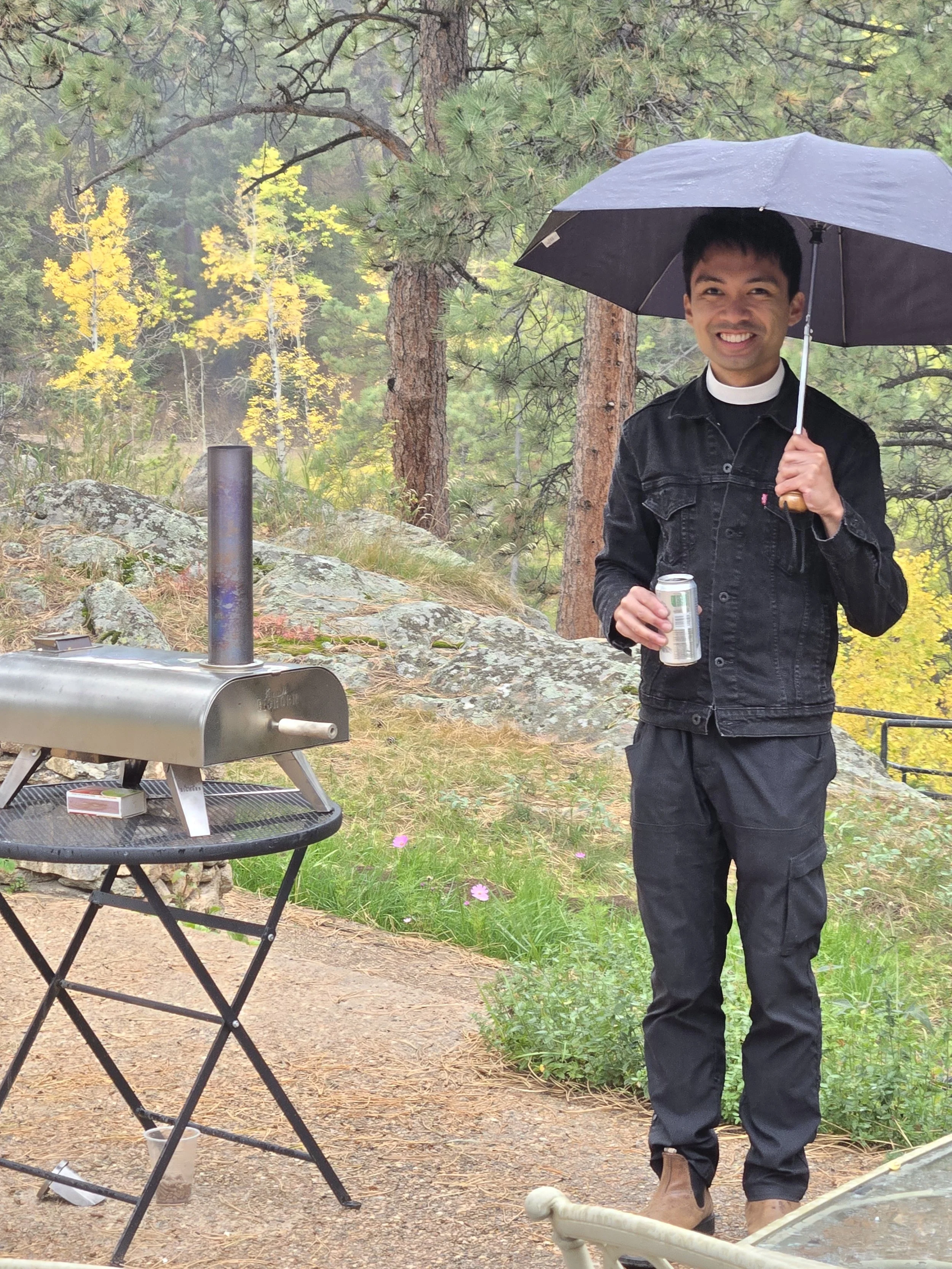 Father Chris enjoying the rain while baking pizza in his new oven.