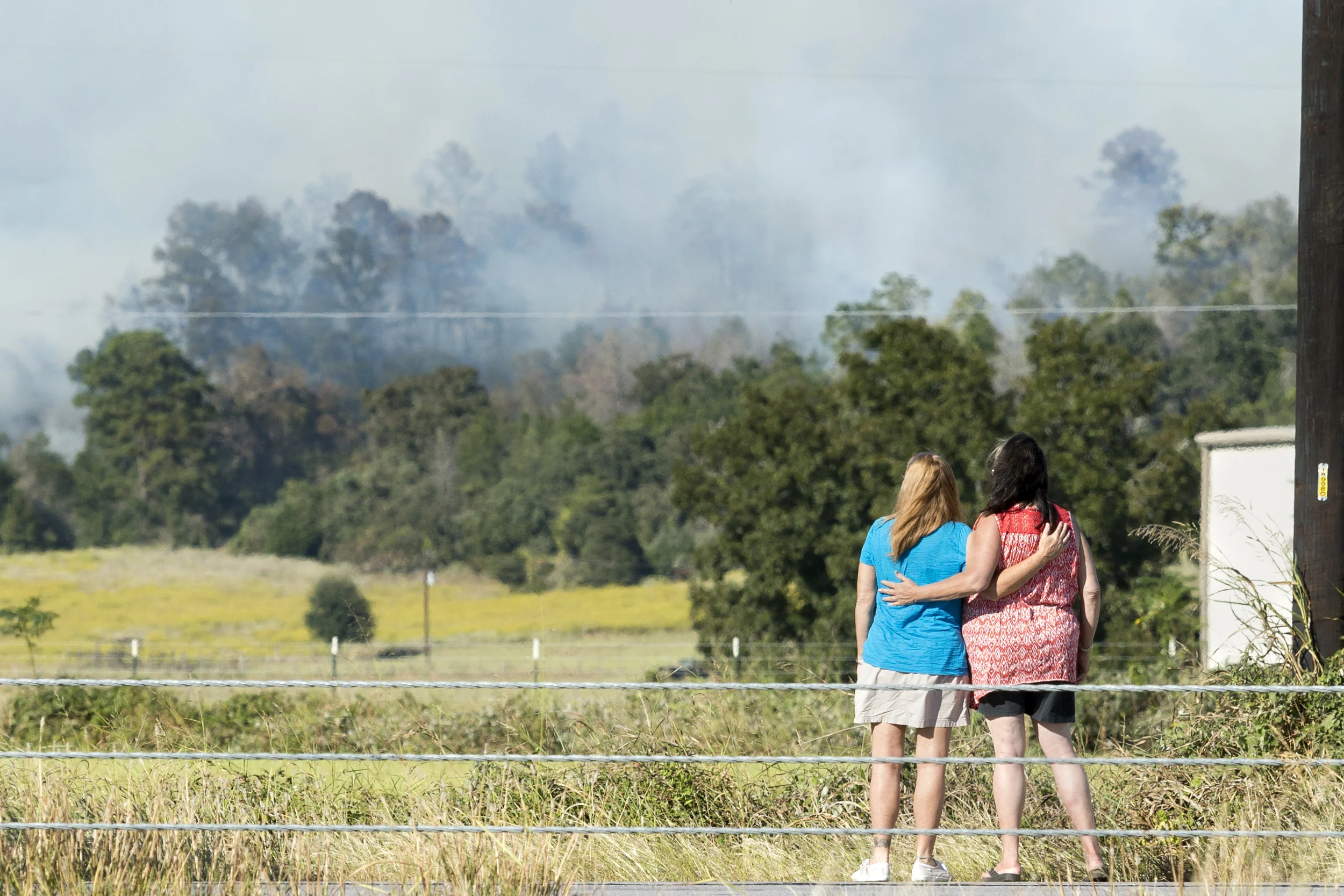 SMITHVILLE, TEXAS - Oct. 14, 2015: The Hidden Pines Fire burns of off SH71 and Kellar Road as two onlookers watch the scene unfold. Miguel Gutierrez Jr. /KUT News.