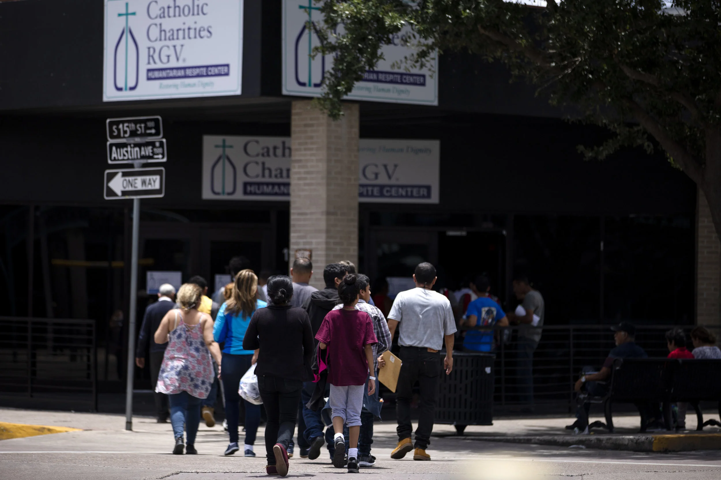A group of migrants is ushered by volunteers to the Catholic Charities Humanitarian Respite Center across the street from the McAllen Central Station in downtown McAllen on June 25, 2019.
