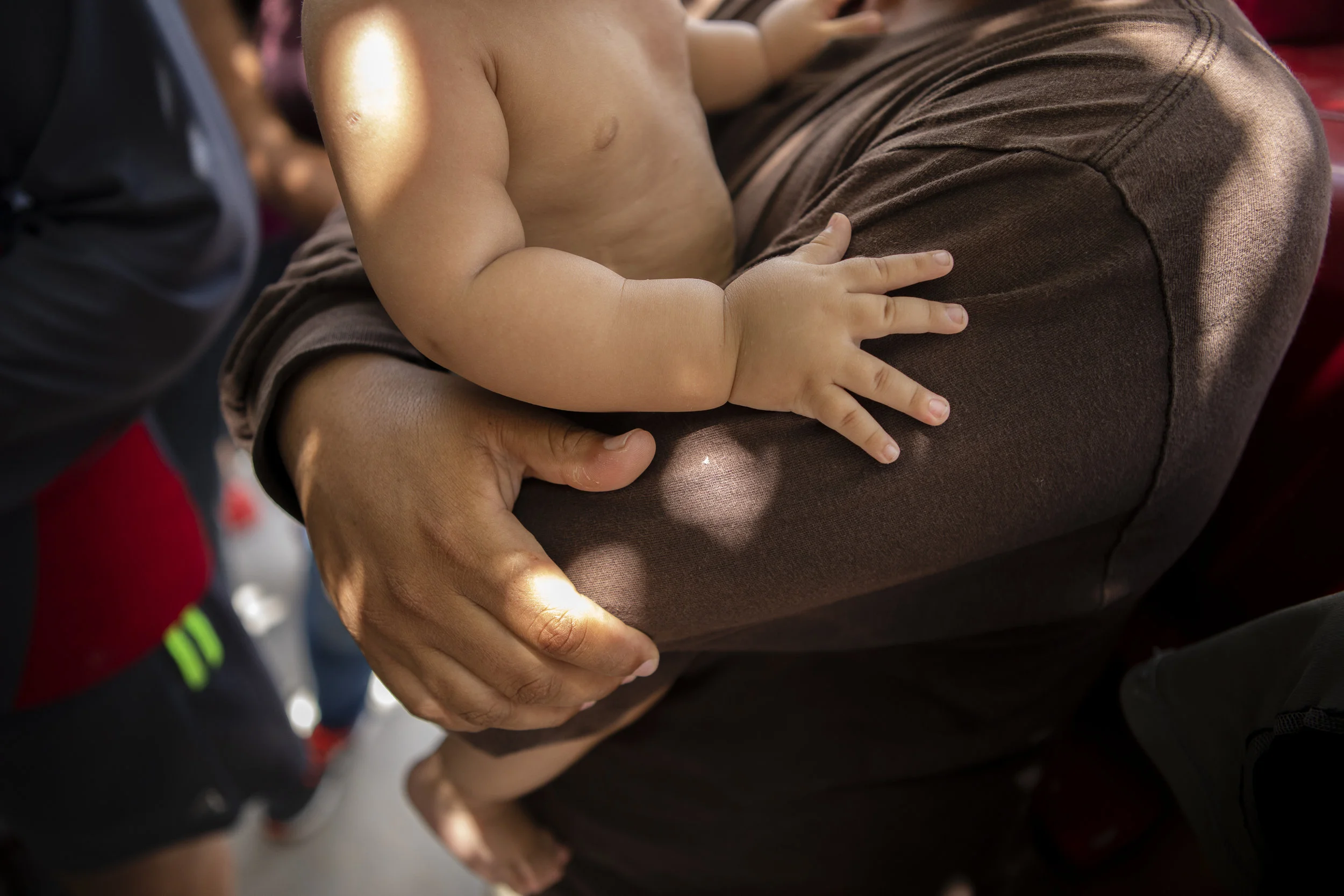 A young man holds a baby at the Senda de Vida migrant shelter in Reynosa, Tamaulipas on June 29, 2019.