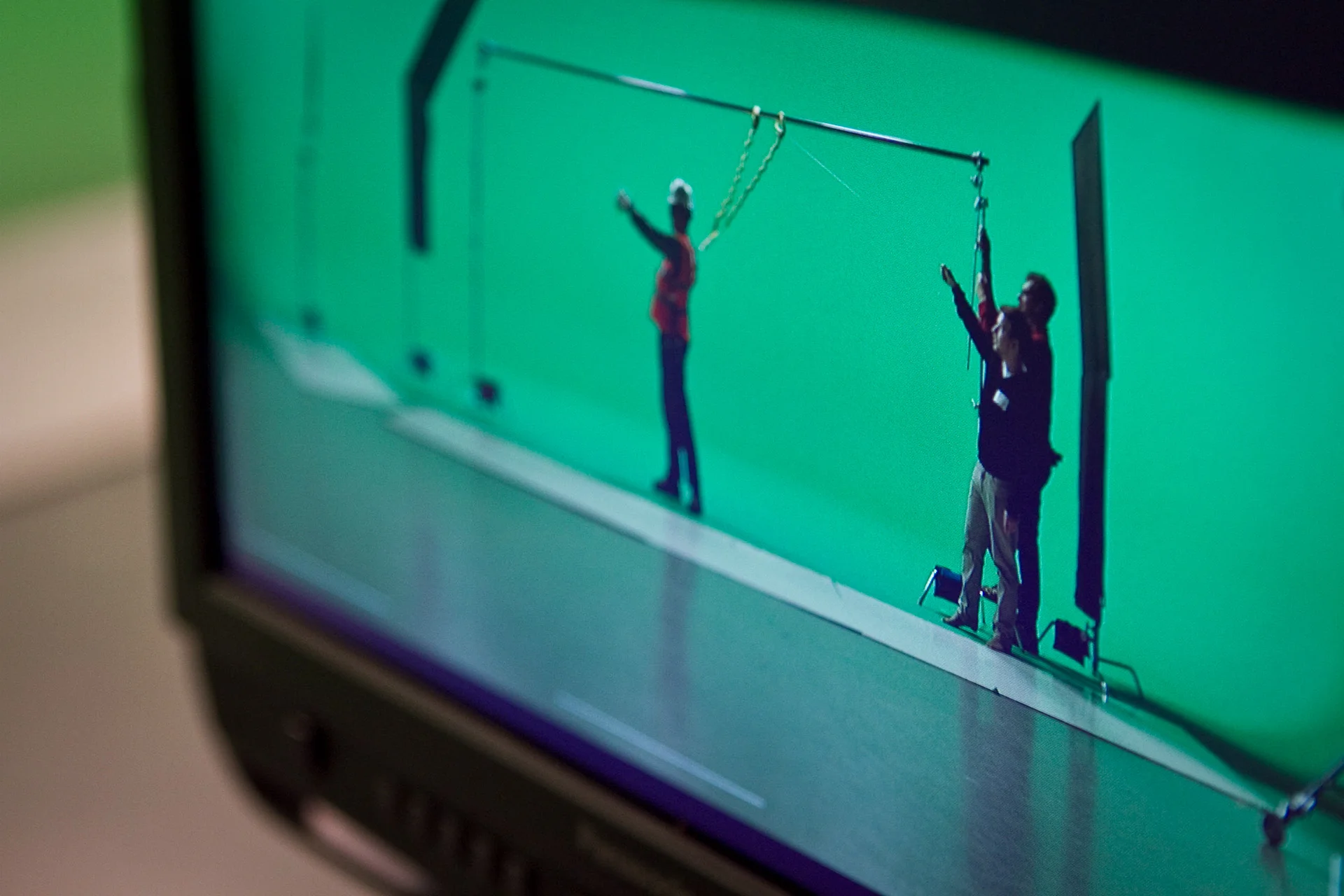 Three men standing on stage in front of green screen