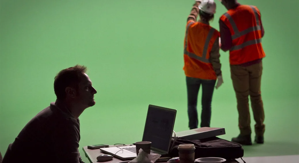 A man looking at a computer with two workers beyond him
