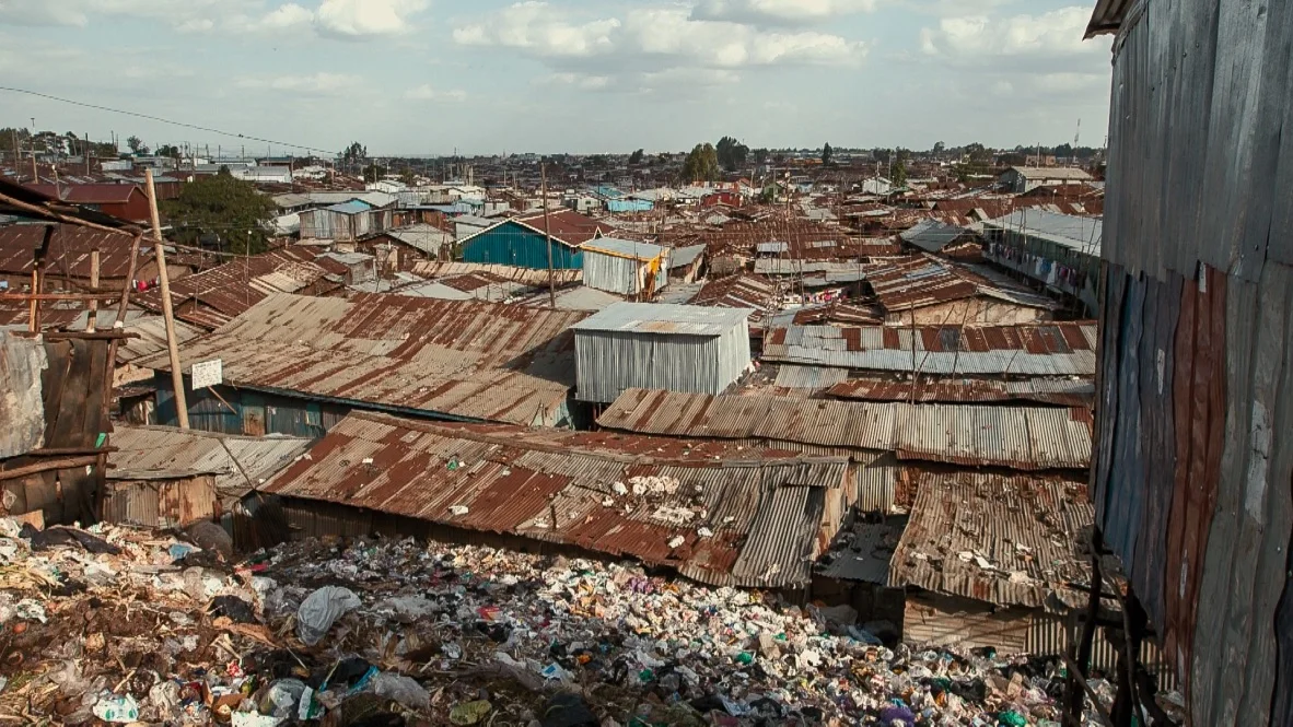 Looking out across the roofs of Kibera, the rubbish, in the foreground, is right up against the wall of houses