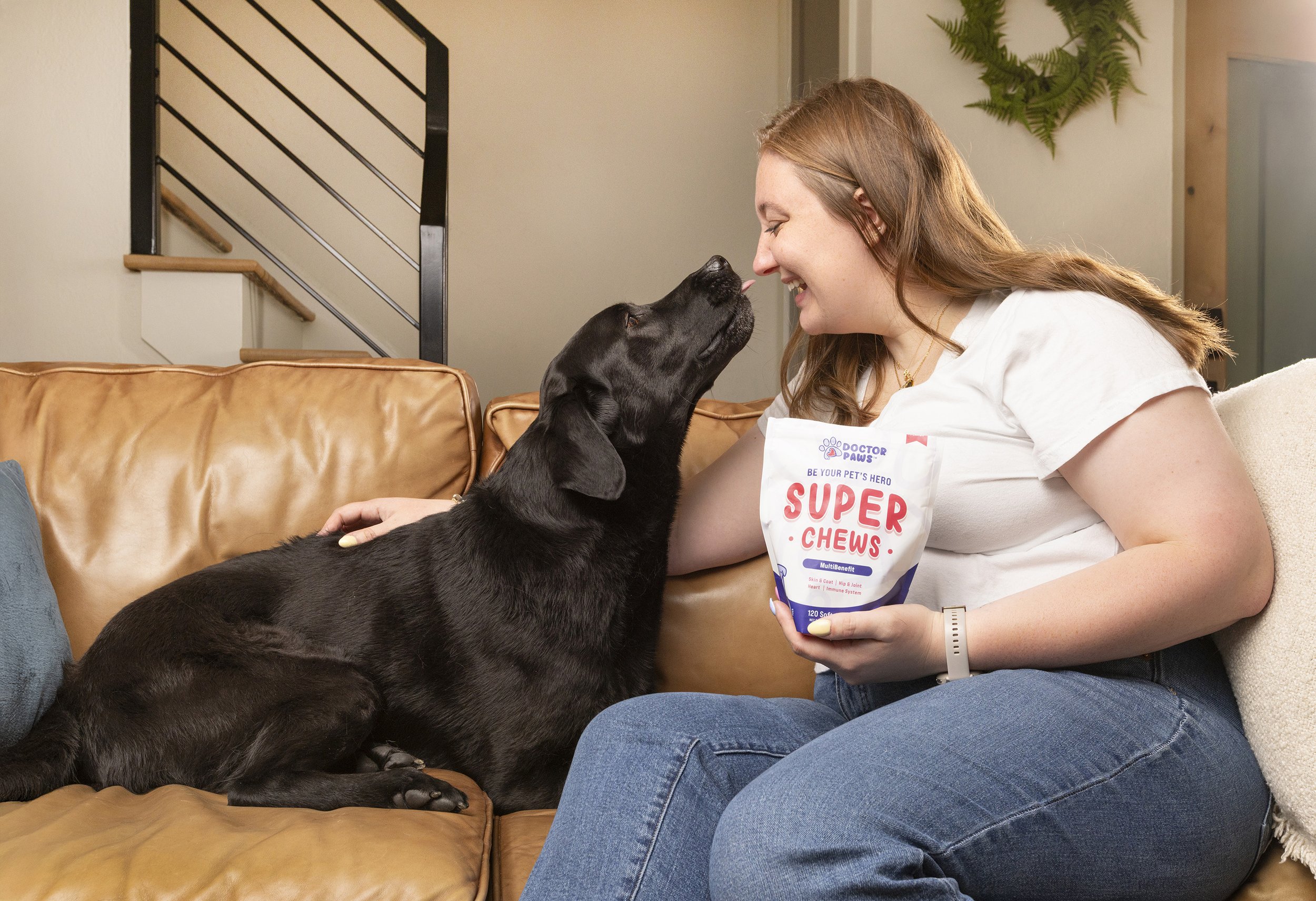 Commercial pet photography lifestyle shot of a woman and her dog smiling while holding a bag of treats.